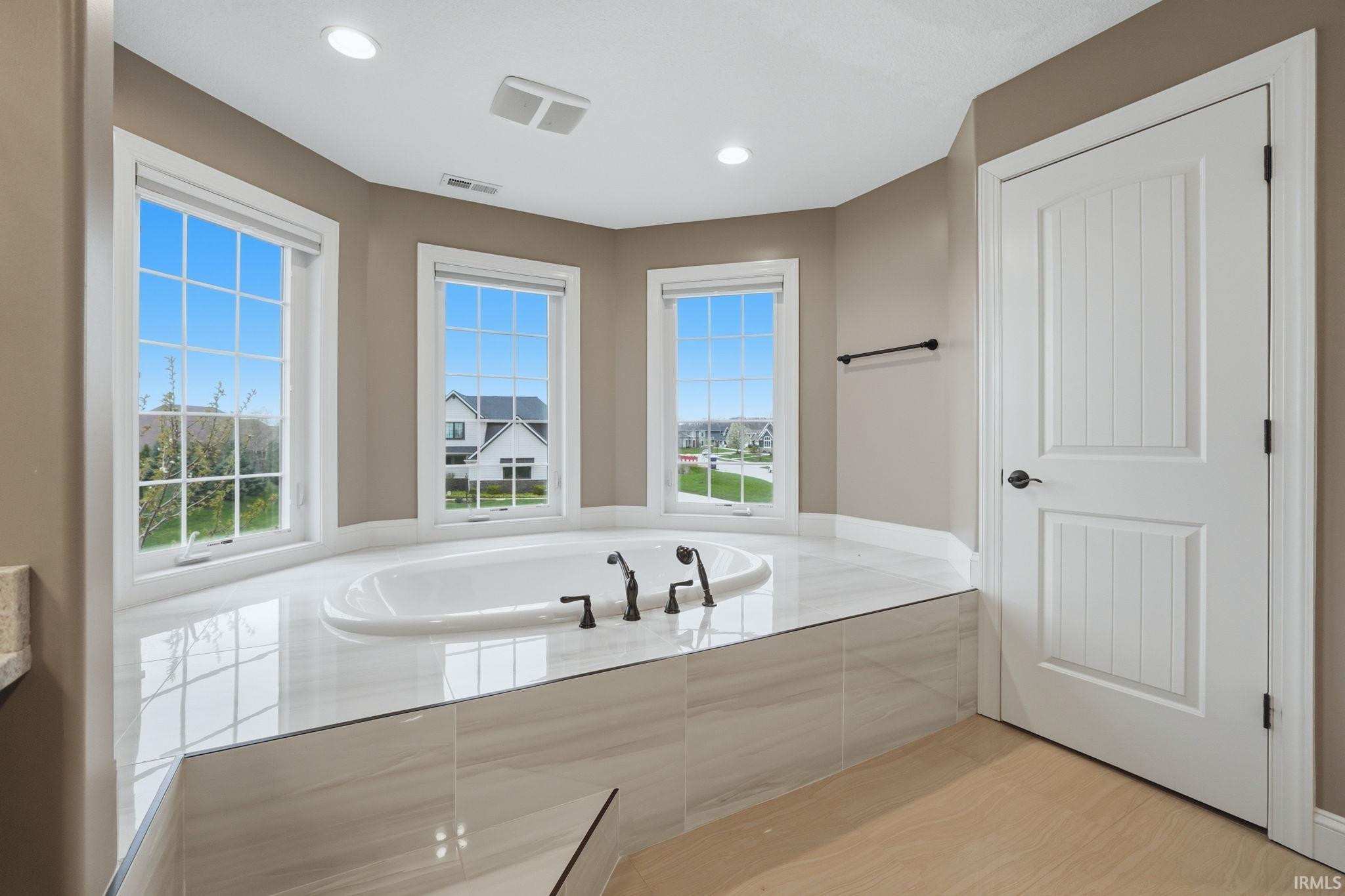 Bathroom with a garden tub, recessed lighting, and light wood finished floors
