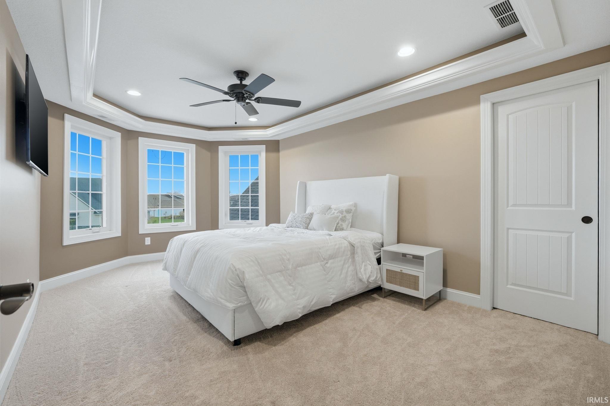Bedroom with ornamental molding, a raised ceiling, recessed lighting, light carpet, and ceiling fan