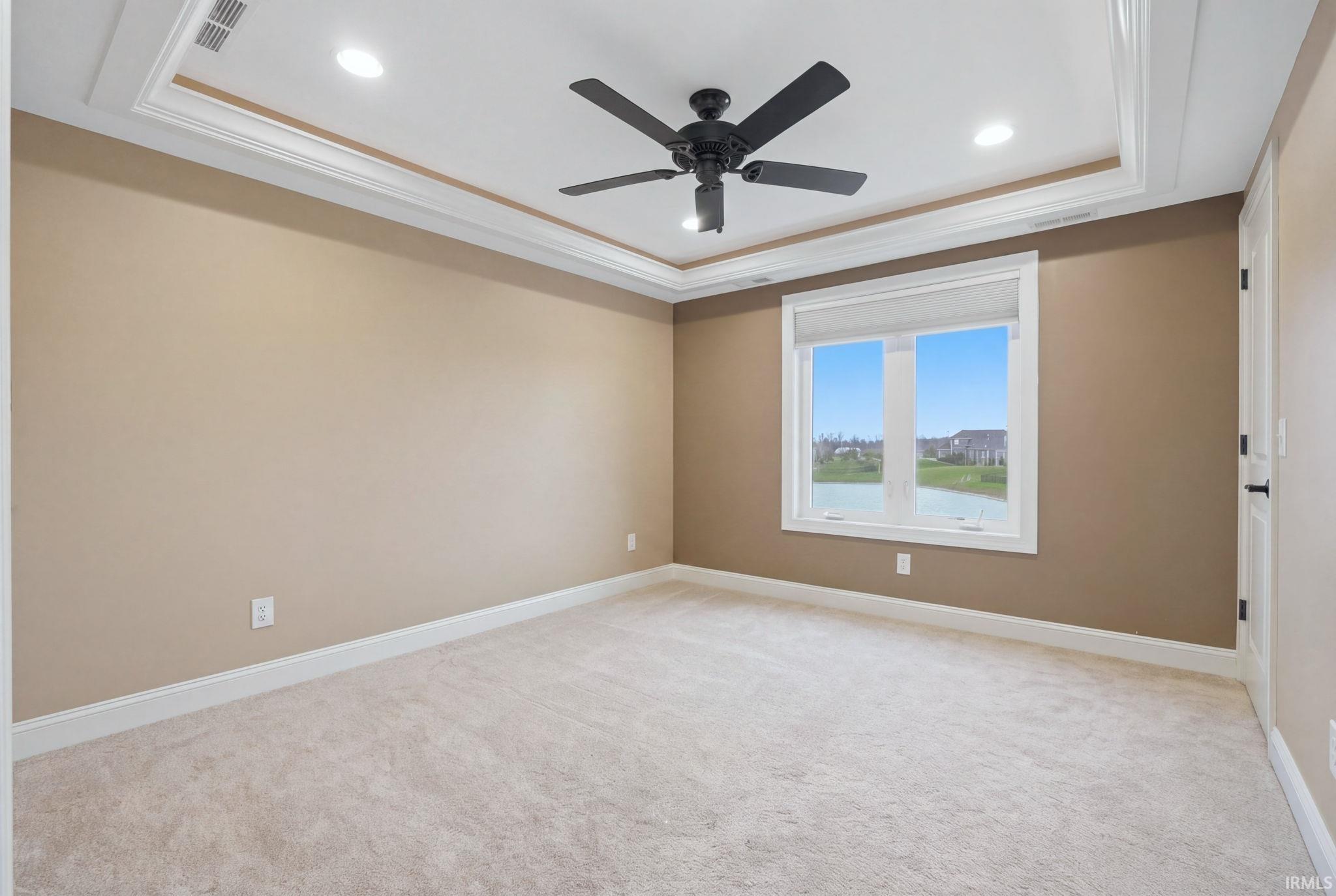 Unfurnished room featuring light colored carpet, ornamental molding, ceiling fan, recessed lighting, and a tray ceiling