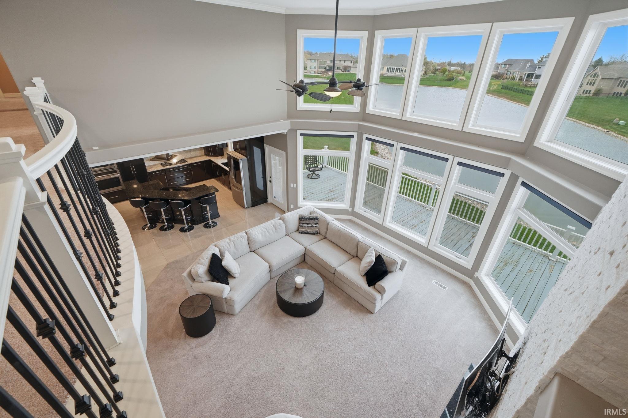 Living room with a high ceiling, a water view, a residential view, and hanging lights