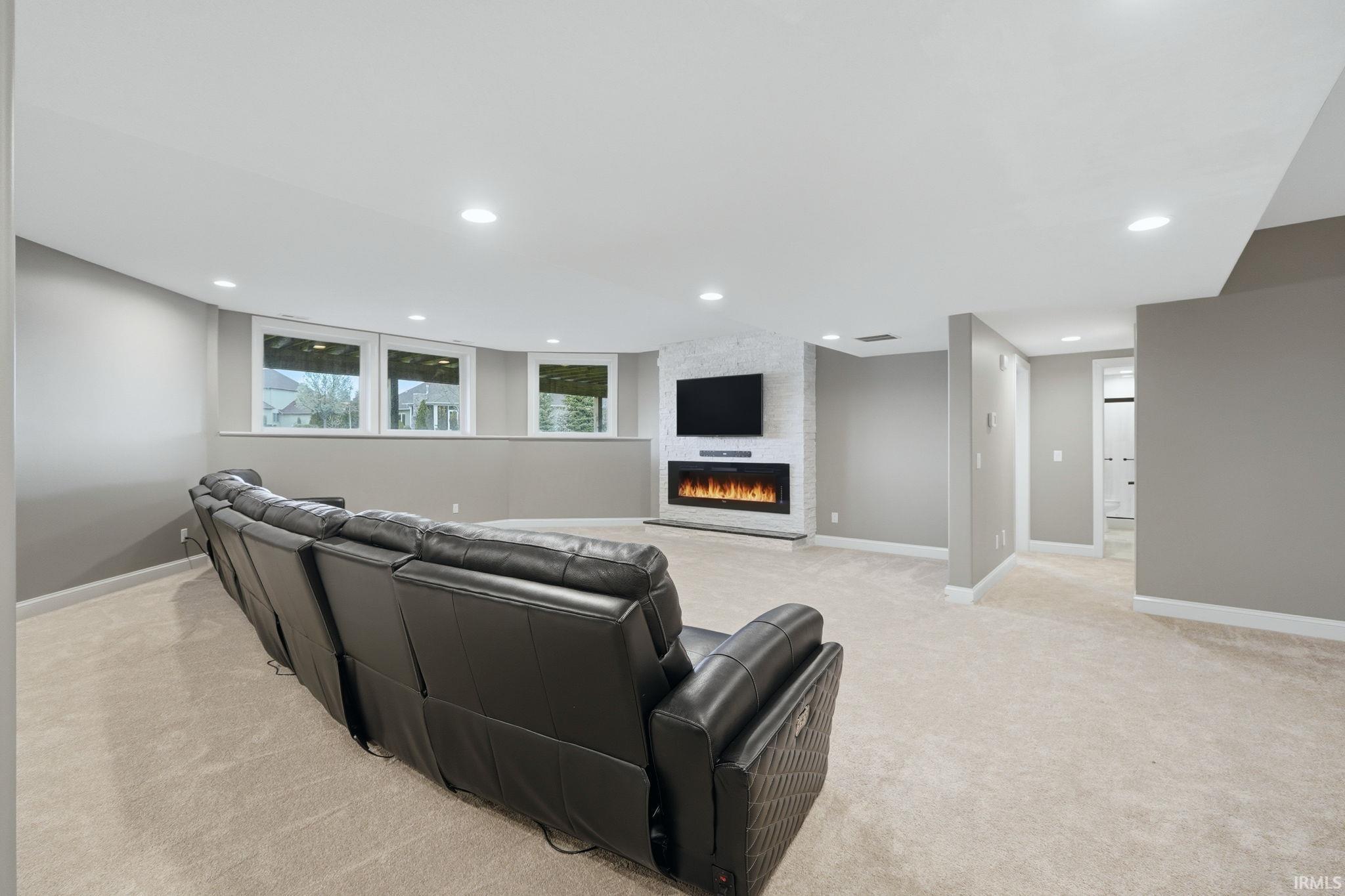 Living room featuring light colored carpet, a large fireplace, and recessed lighting