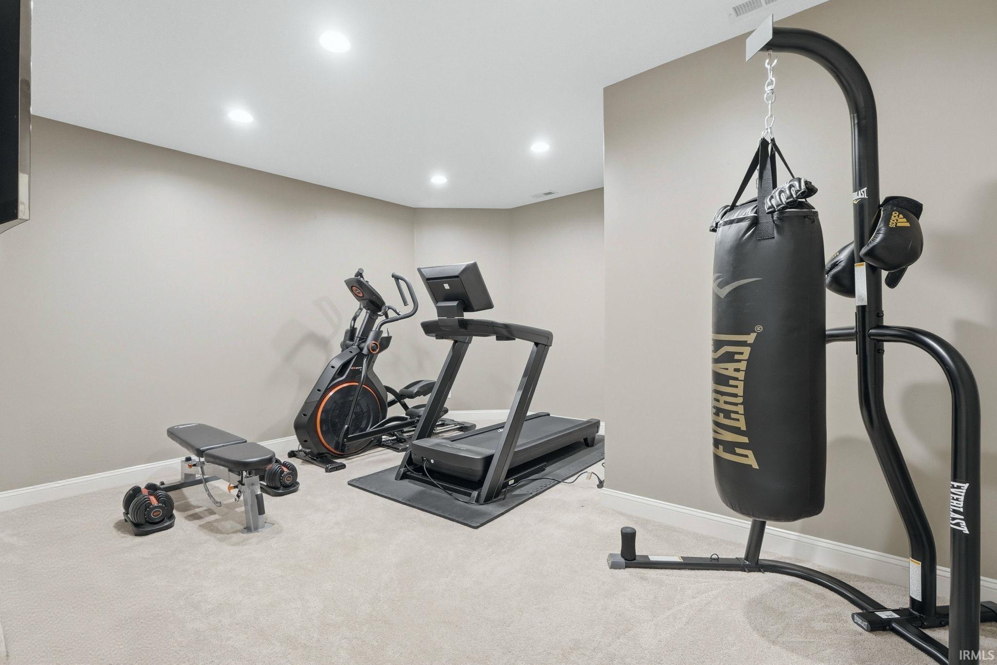 Workout room with light colored carpet and recessed lighting