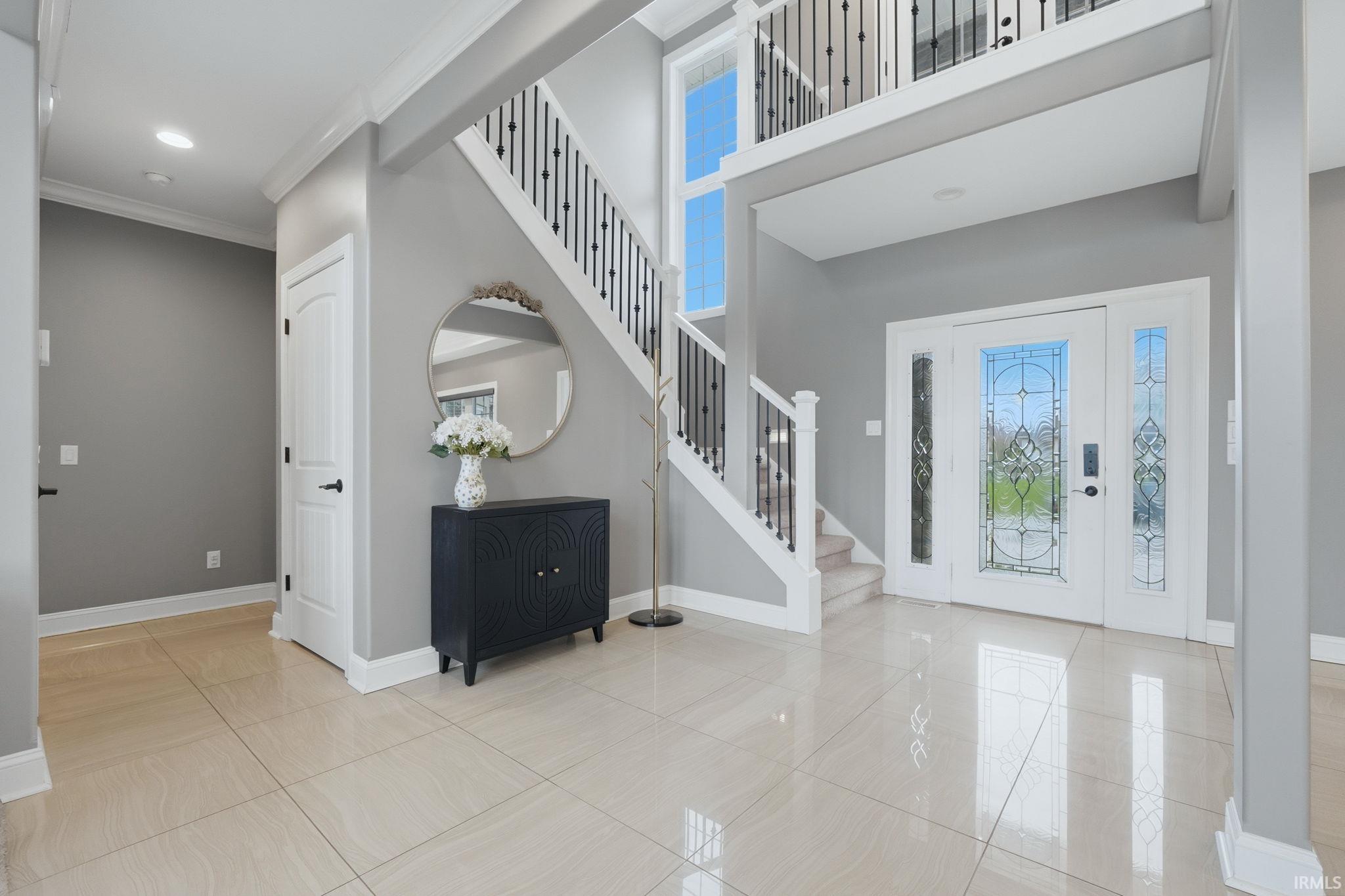 Foyer featuring a high ceiling, ornamental molding, light tile patterned floors, and recessed lighting
