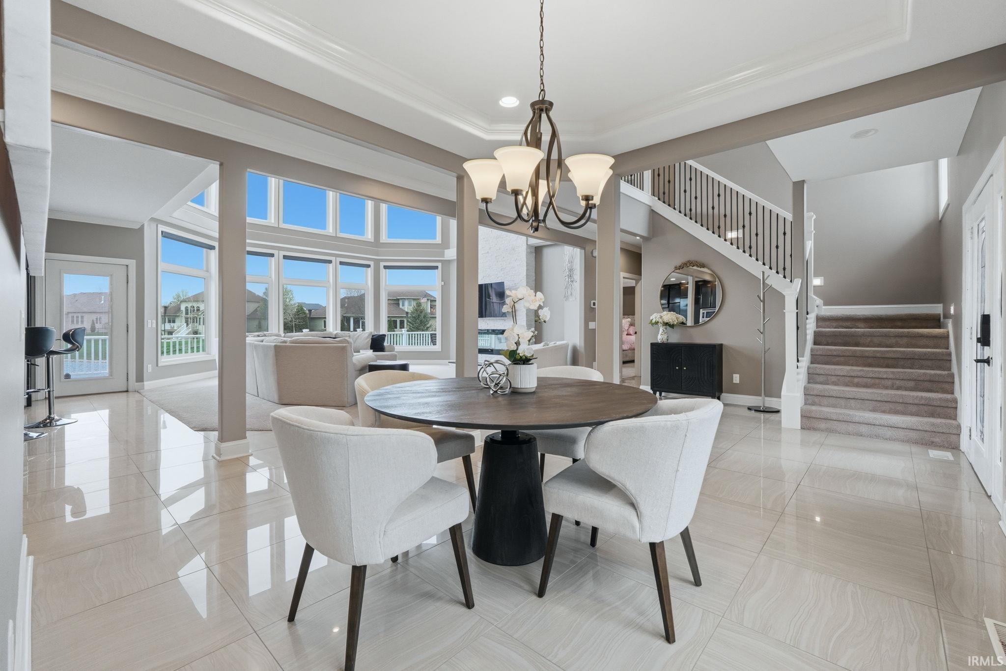 Dining space with suspended lighting, light tile patterned flooring, crown molding, and a raised ceiling