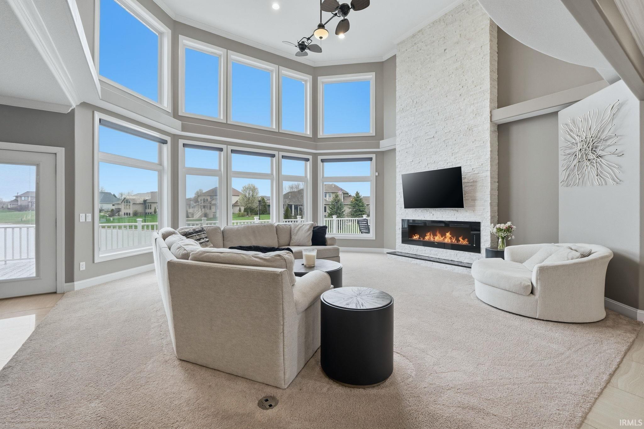 Living room with a stone fireplace, a high ceiling, and a residential view