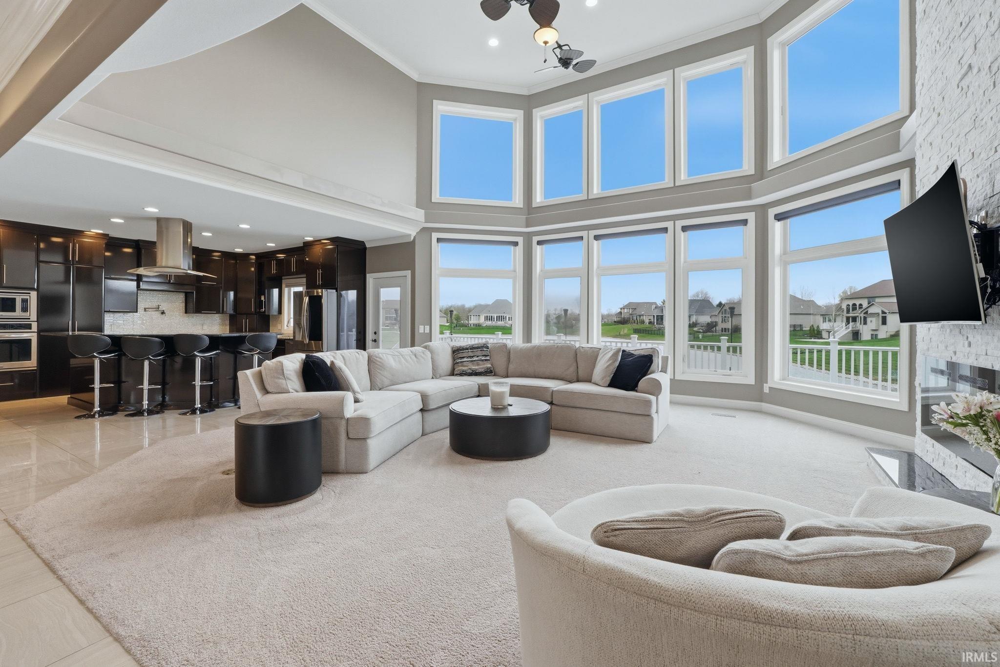 Living room with recessed lighting, a high ceiling, a residential view, ornamental molding, and a fireplace