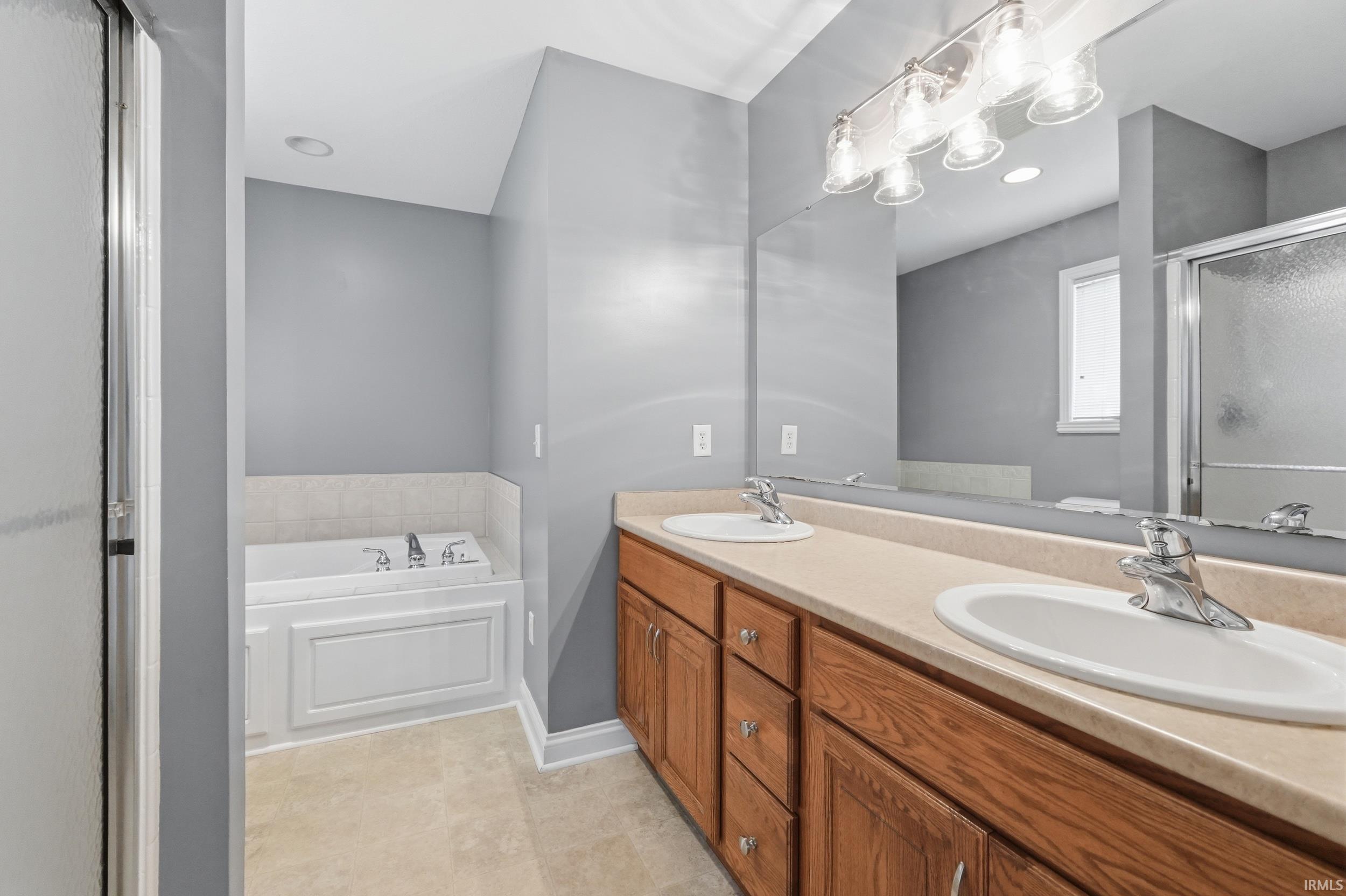 Bathroom with a garden tub, a stall shower, double vanity, and recessed lighting