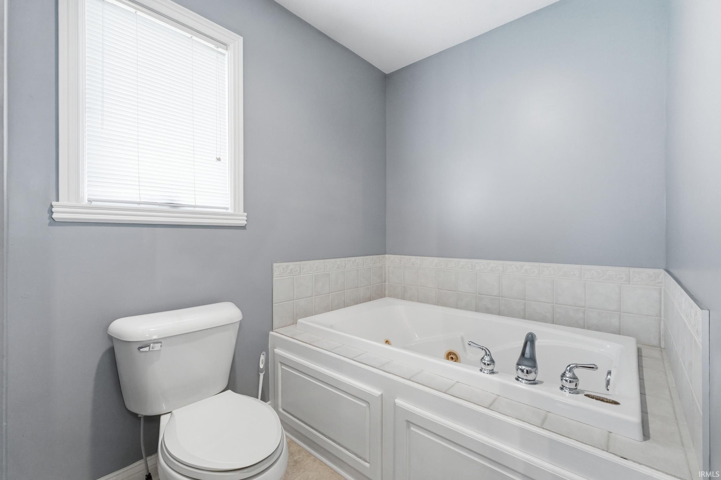 Bathroom with a tub with jets and toilet