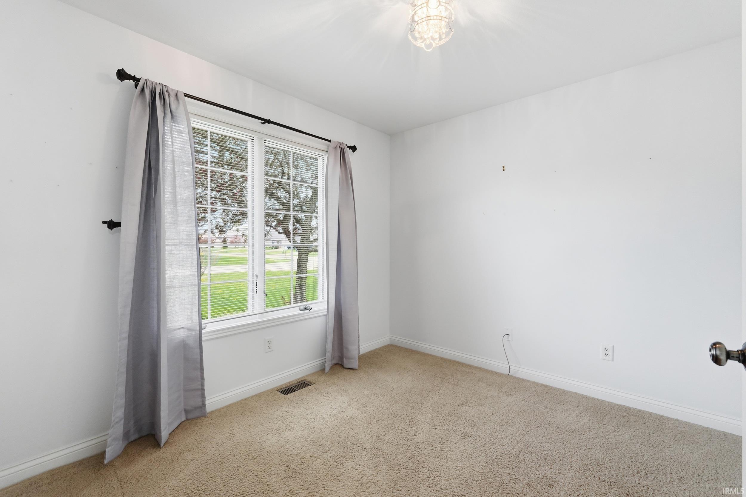 Empty room featuring light carpet and baseboards
