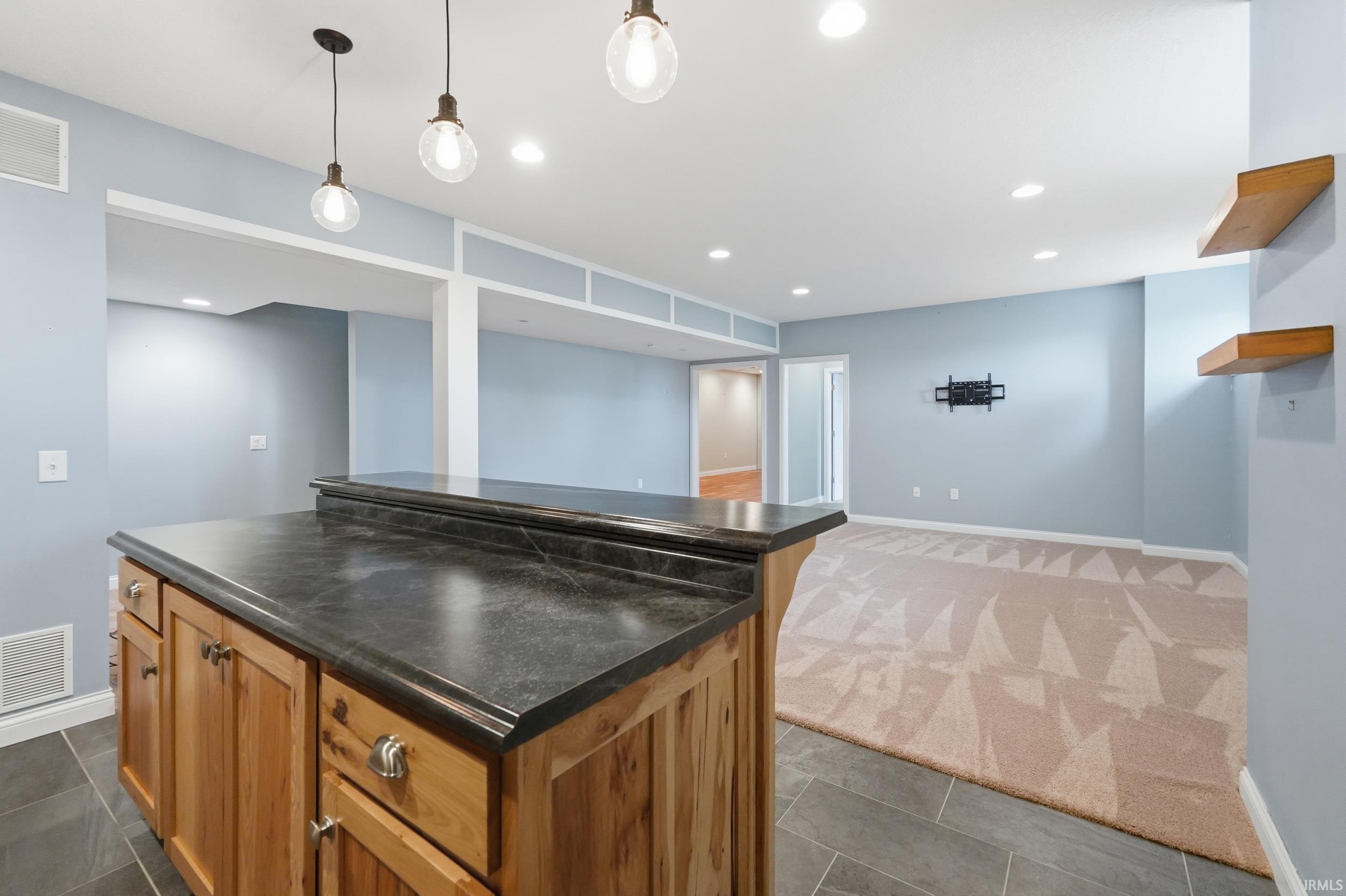 Kitchen featuring dark countertops, open shelves, wood finish cabinetry, a kitchen island, and open floor plan