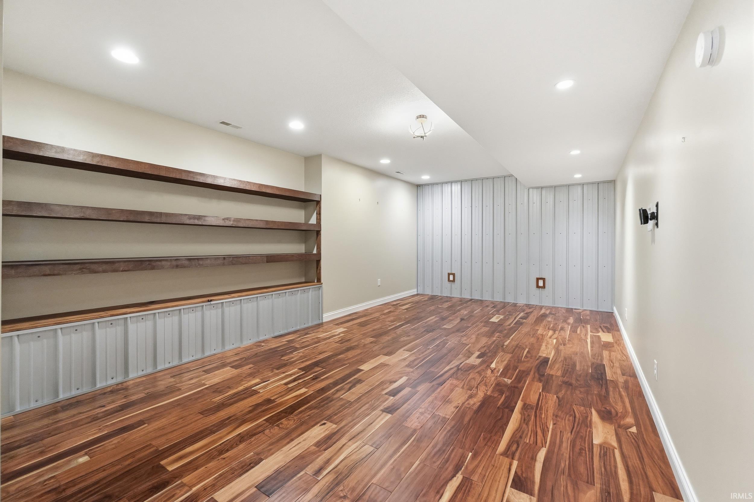 Basement featuring dark wood-style floors, recessed lighting, and an accent wall