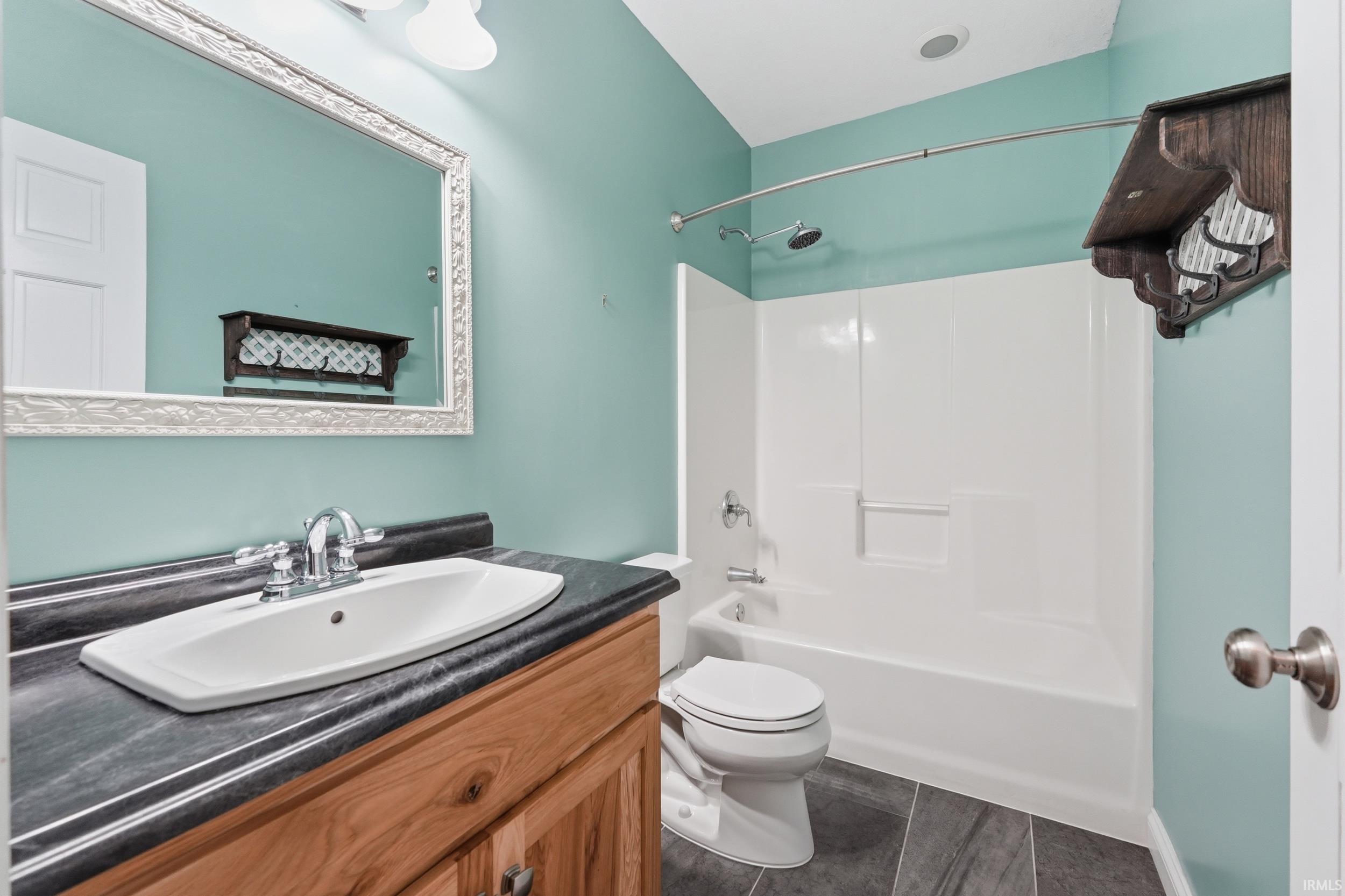 Bathroom with vanity, bathing tub / shower combination, and dark tile patterned flooring