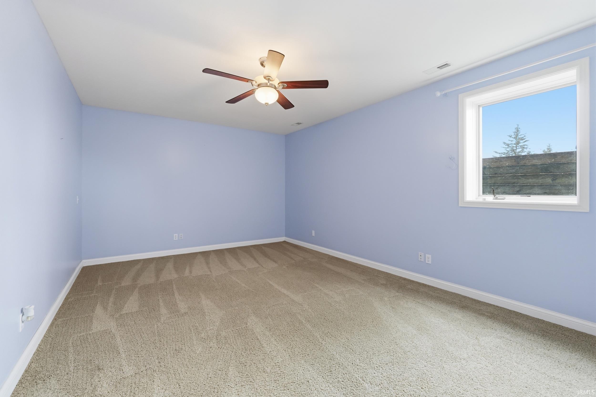 Spare room featuring light colored carpet and a ceiling fan