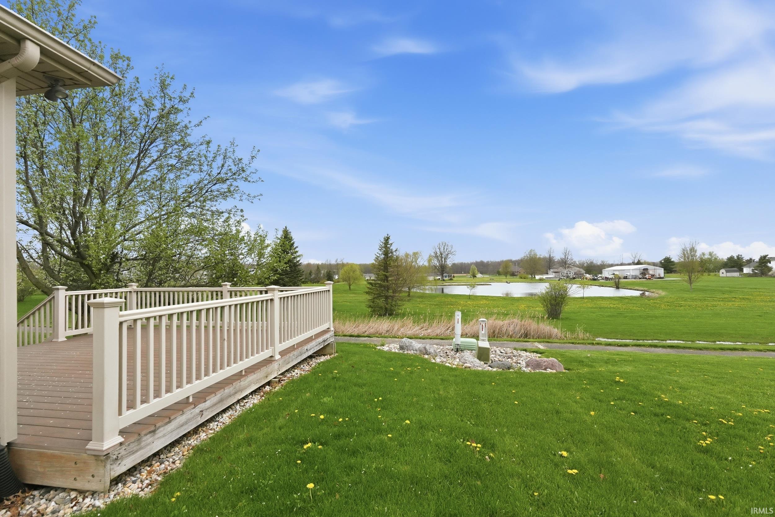 View of green lawn with a deck with water view