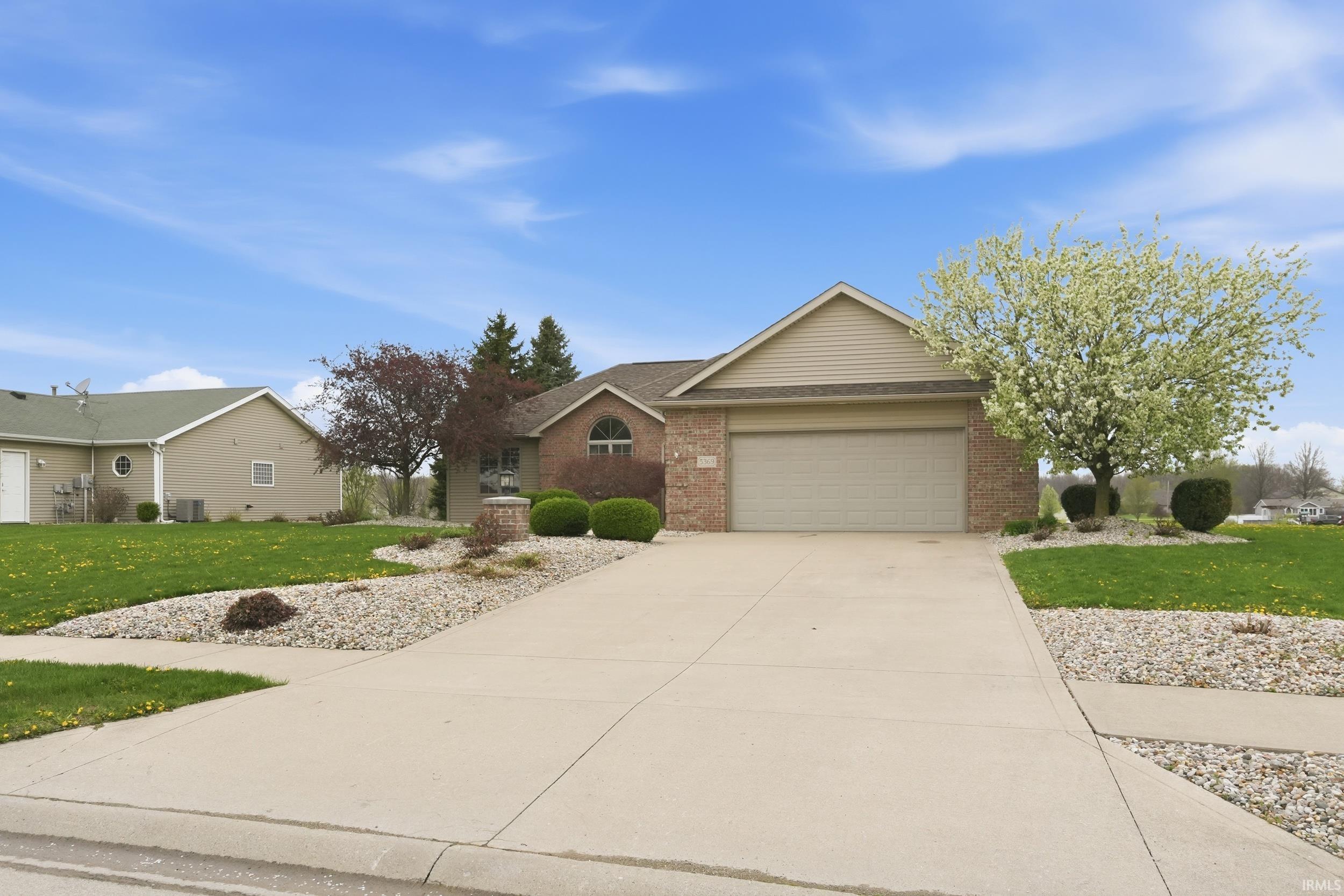 Ranch-style house with a front yard, brick siding, a garage, driveway, and a shingled roof
