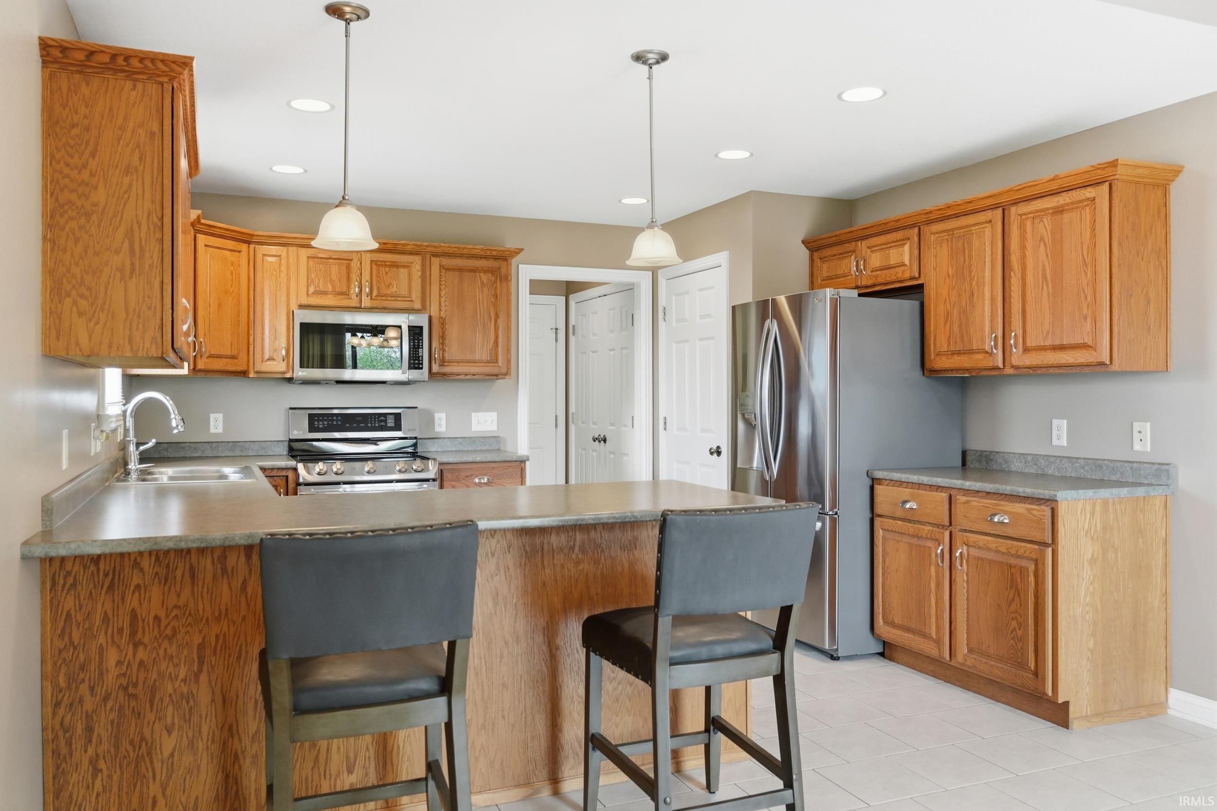 Kitchen with a peninsula, stainless steel appliances, a breakfast bar area, and pendant lighting