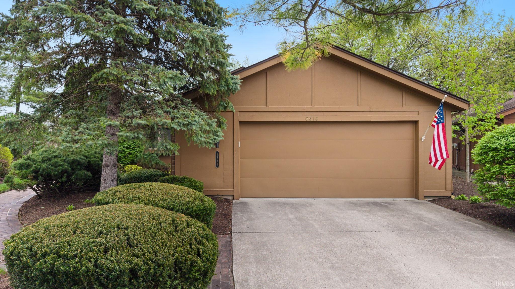 View of front facade featuring driveway, an attached garage, an outbuilding, and board and batten siding