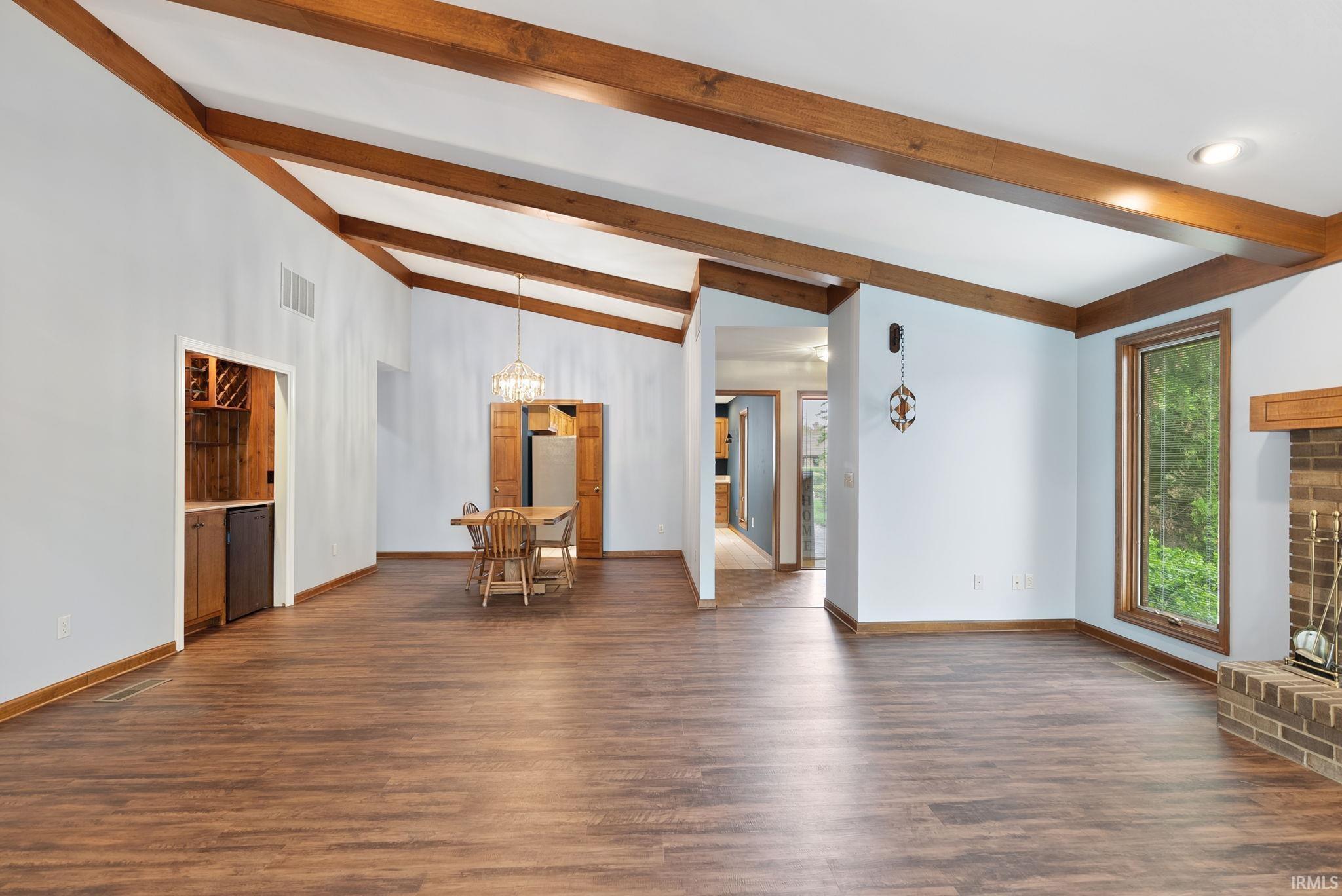 Unfurnished living room with beam ceiling and dark wood-type flooring