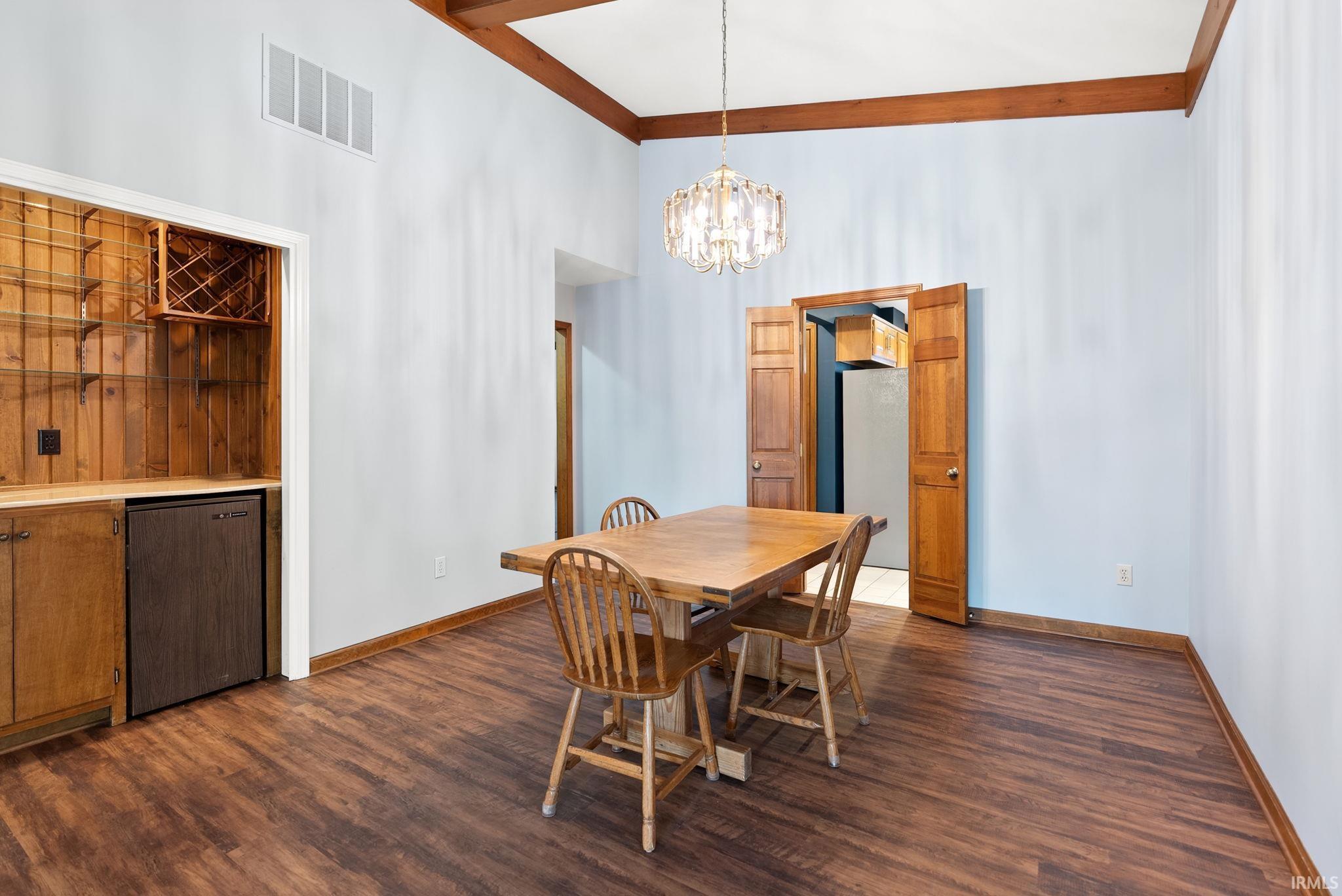 Dining room featuring dark wood-style flooring, a chandelier, and a high ceiling