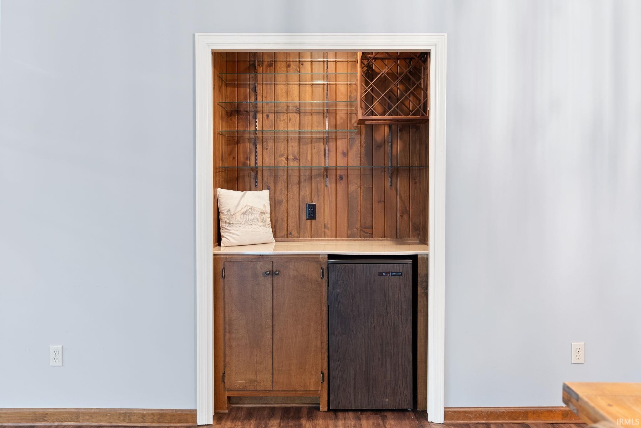 Bar area with fridge and dark wood-style flooring
