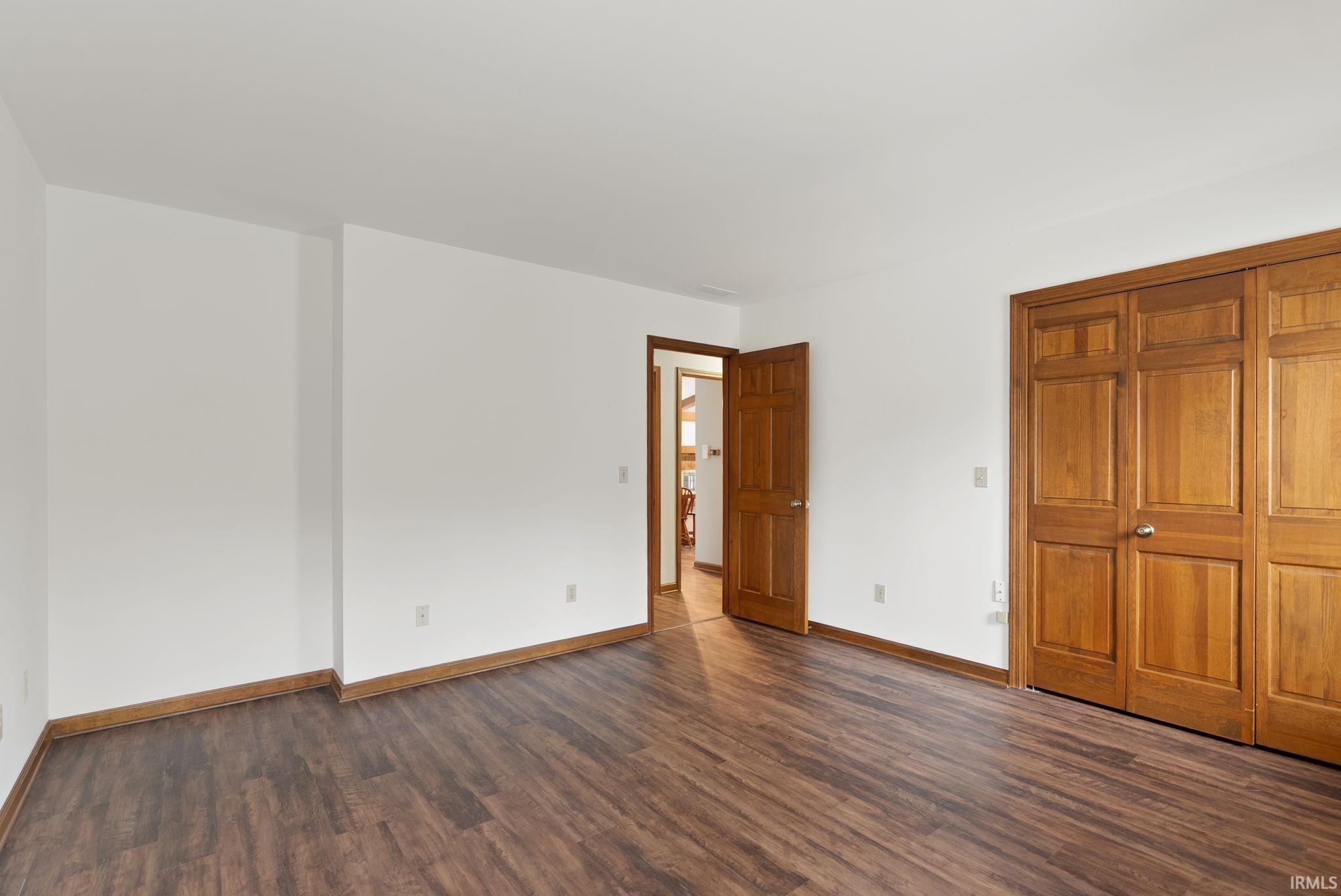 Unfurnished bedroom with dark wood finished floors and baseboards