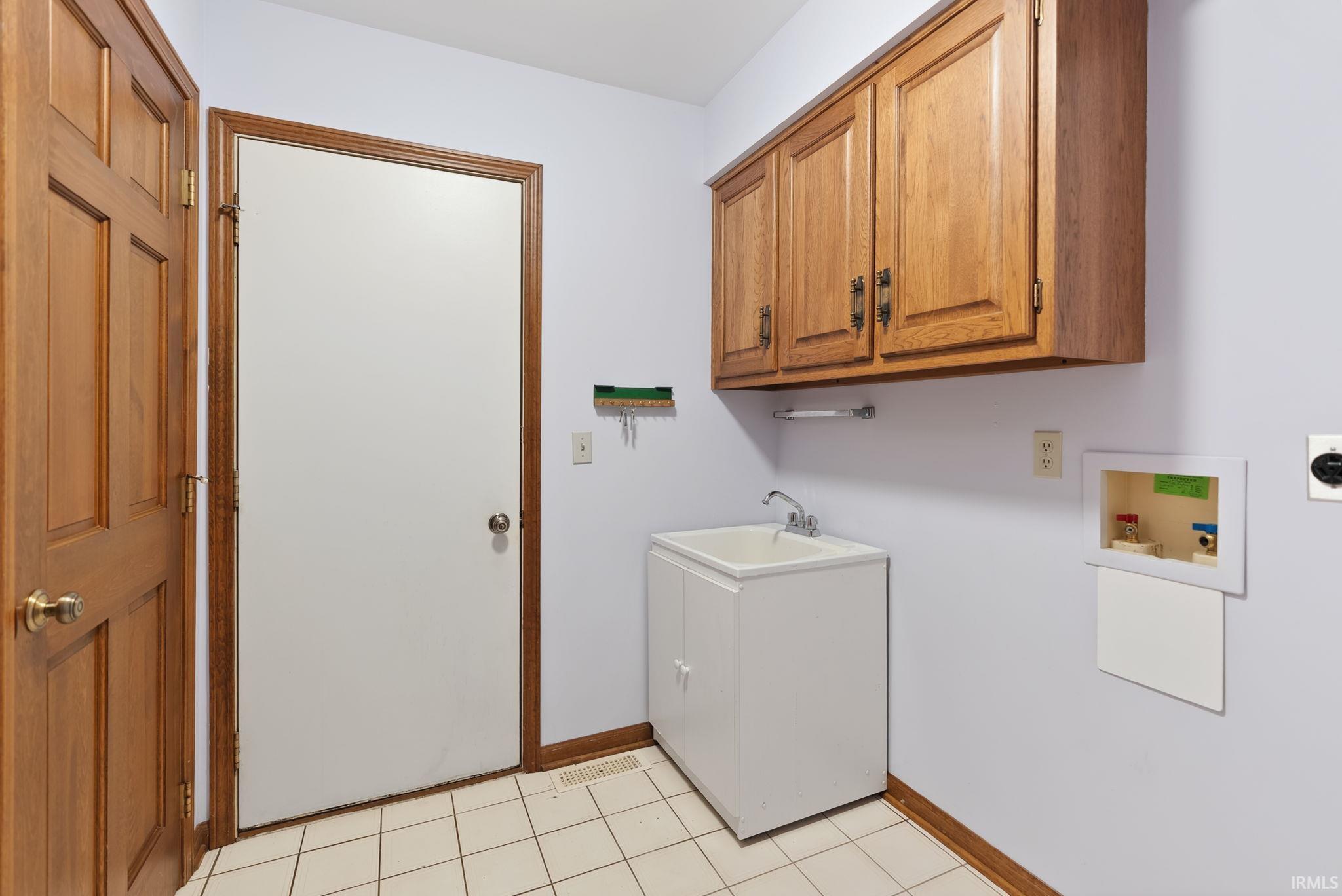 Laundry room with hookup for a washing machine, cabinet space, light tile patterned floors, and electric dryer hookup