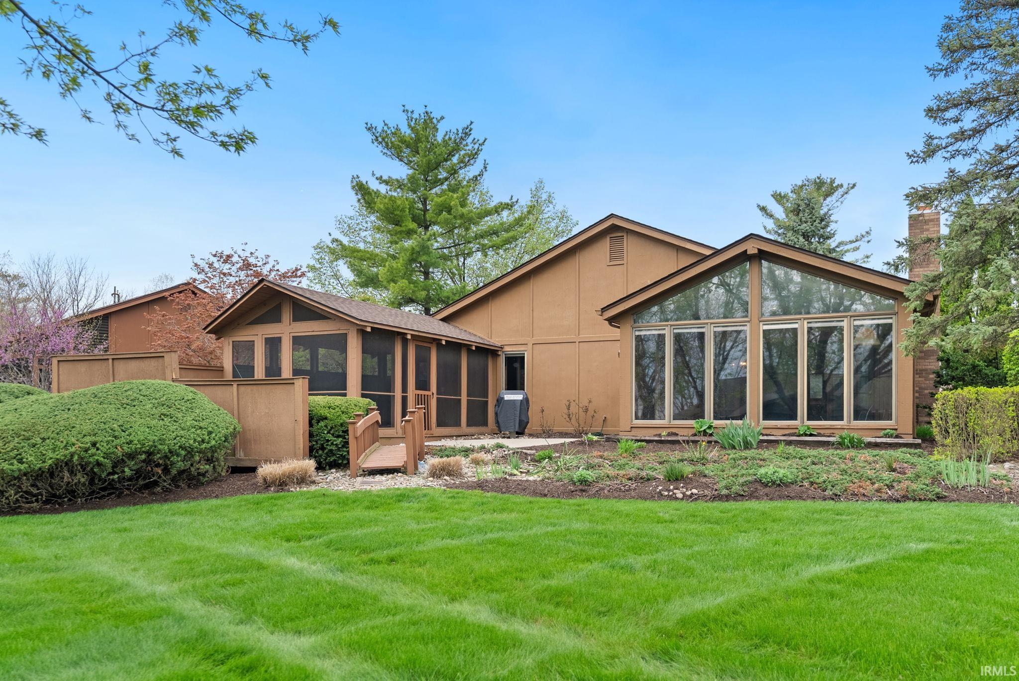 Back of property with a sunroom, a lawn, and a chimney
