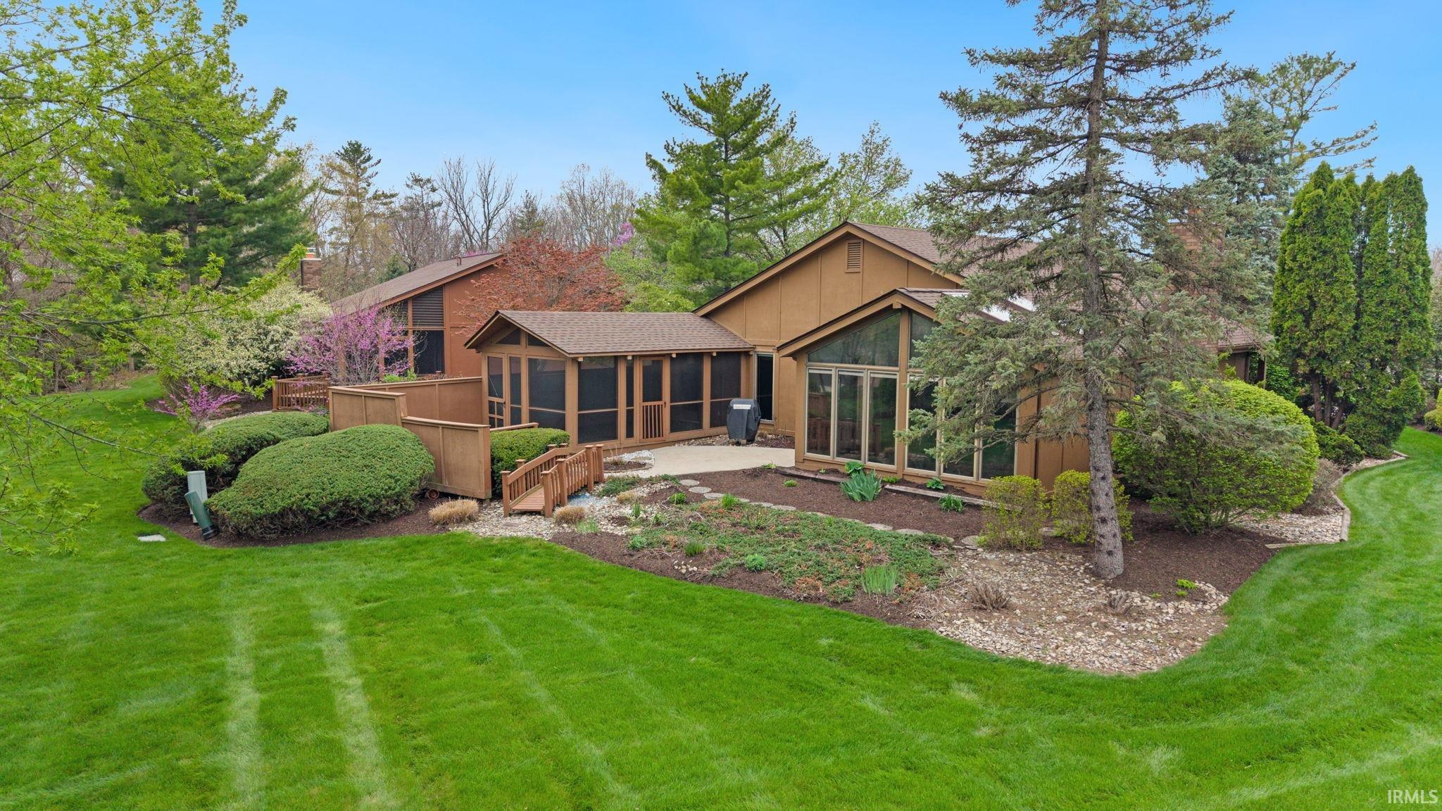 Rear view of house featuring a sunroom and a lawn