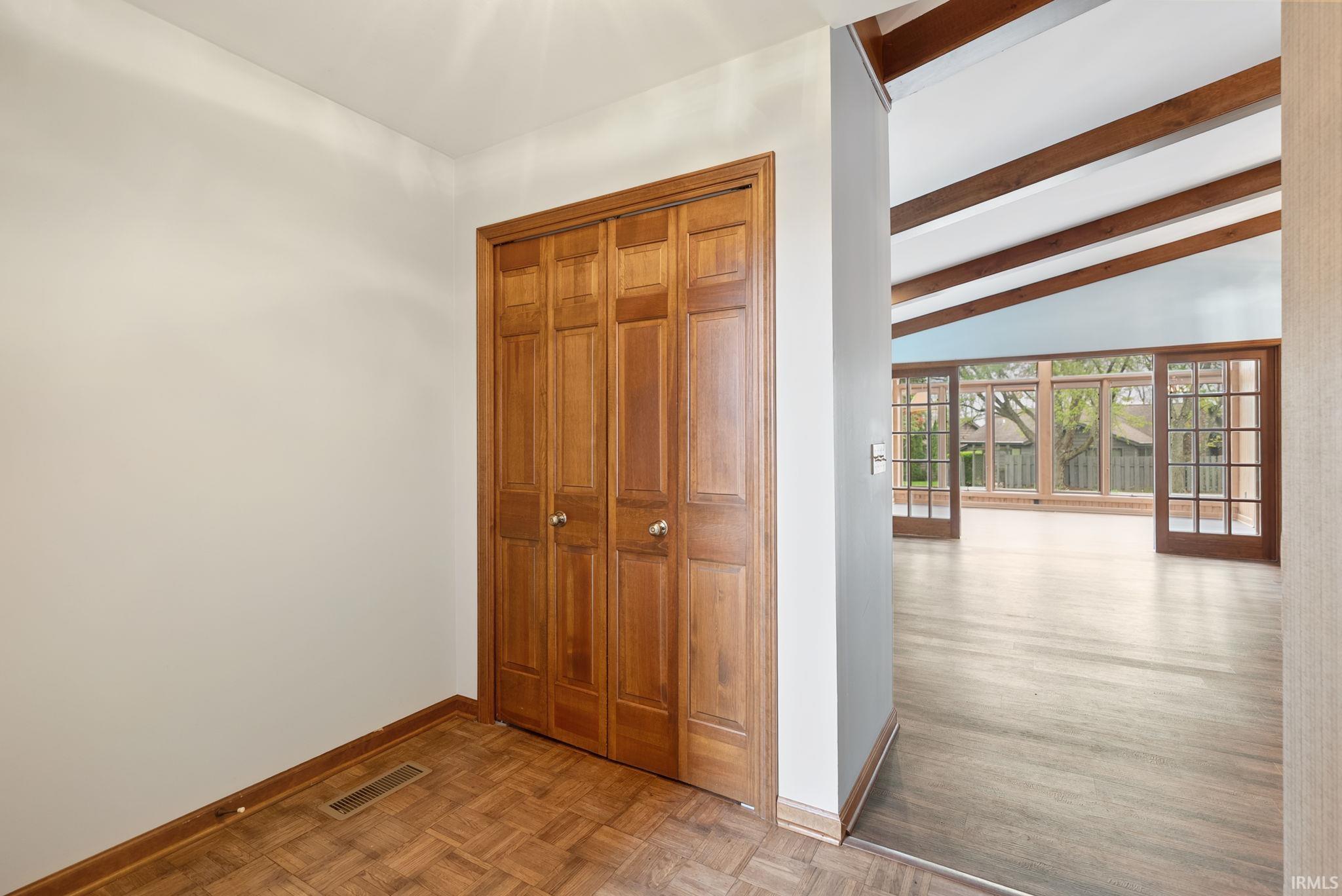 Hallway with parquet flooring and vaulted ceiling with beams