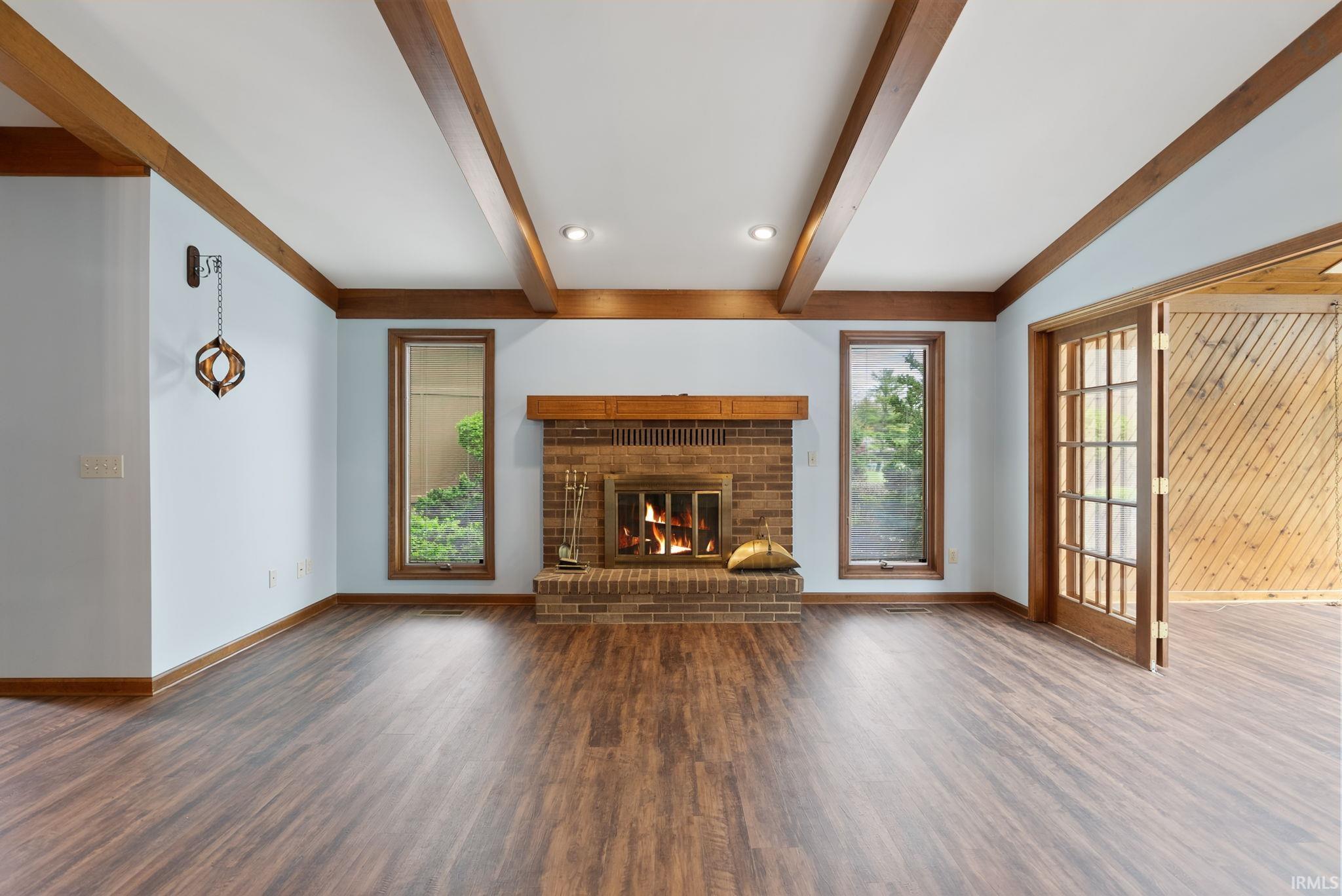 Unfurnished living room featuring a fireplace, dark wood-style floors, beam ceiling, and recessed lighting