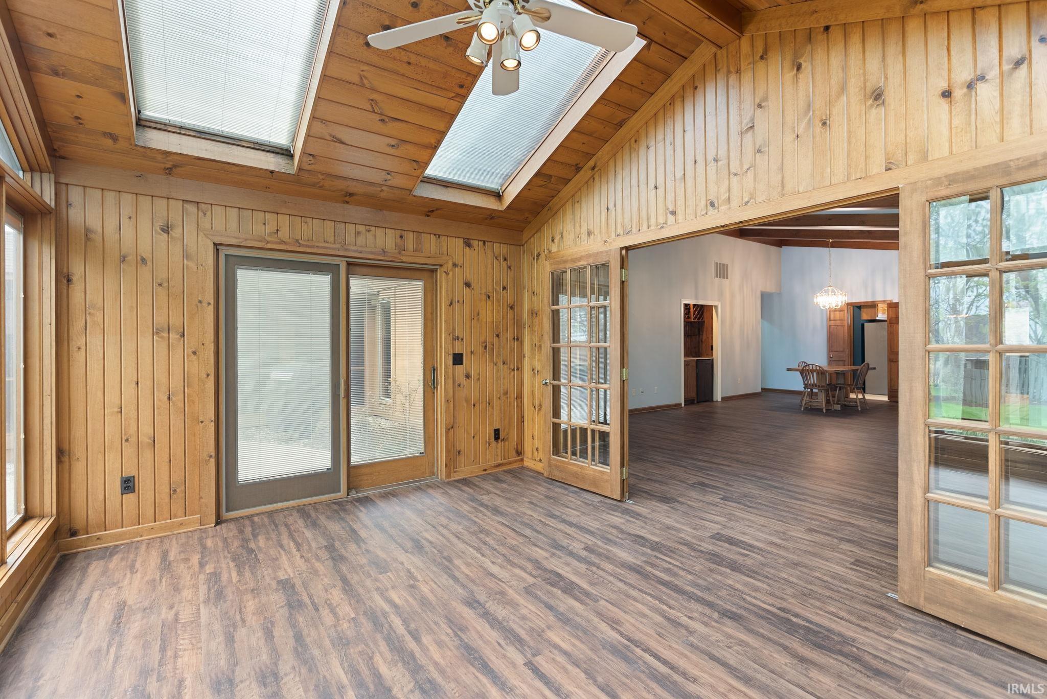 Unfurnished room with dark wood finished floors, a ceiling fan, plenty of natural light, french doors, and a vaulted wood ceiling