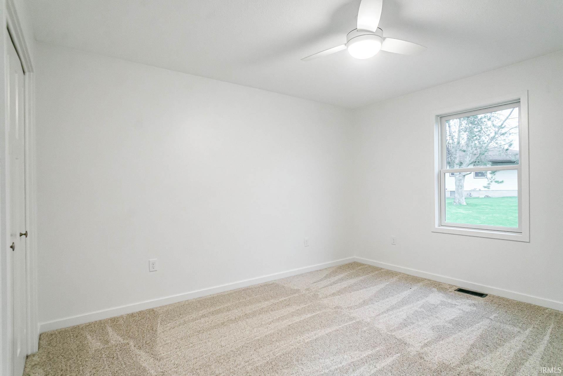 Unfurnished bedroom with light colored carpet, a ceiling fan, and a closet