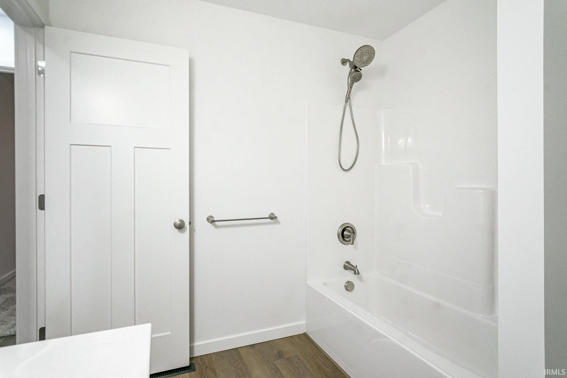 Full bath with shower / bath combination and dark wood-style floors