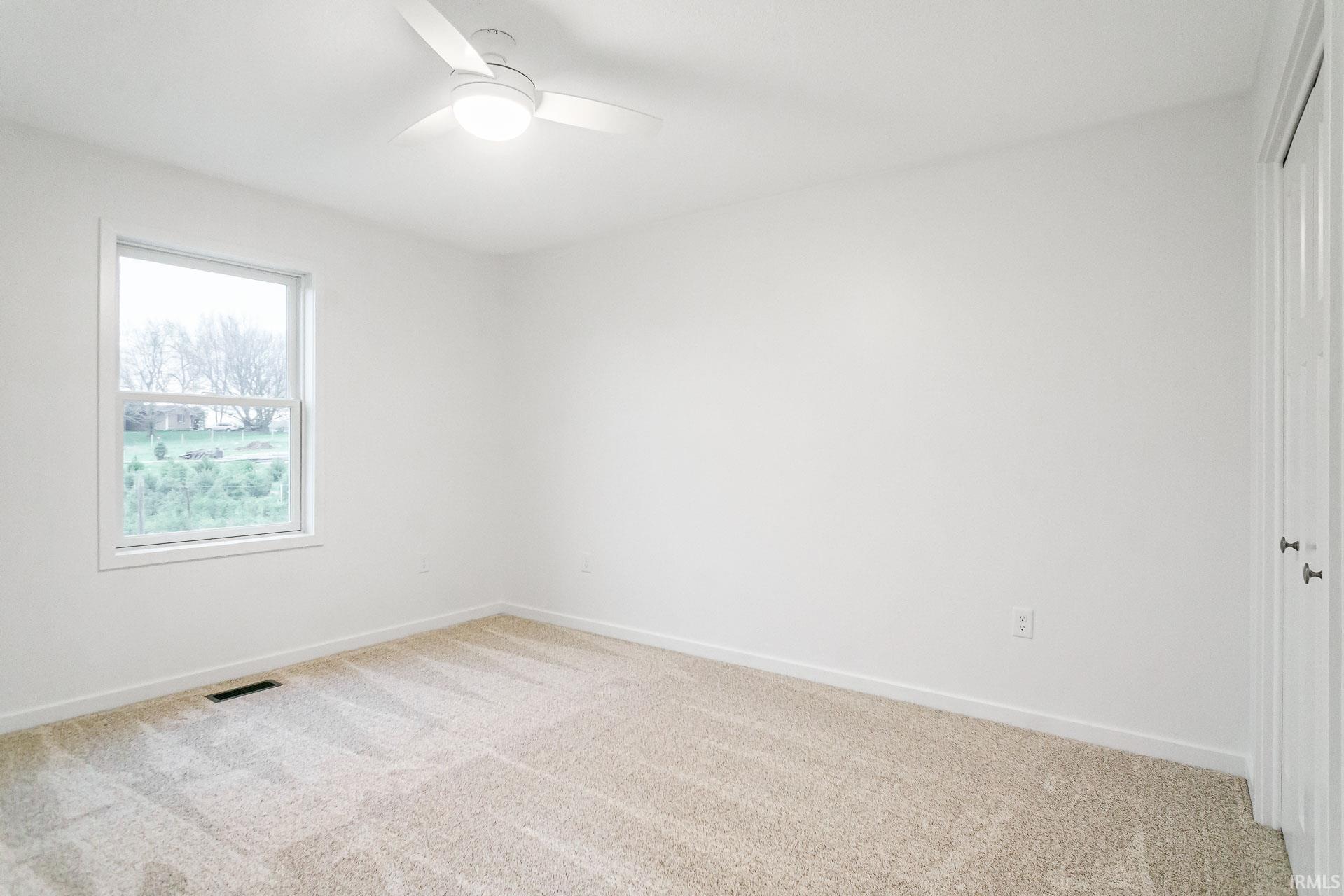 Unfurnished room with light colored carpet and ceiling fan