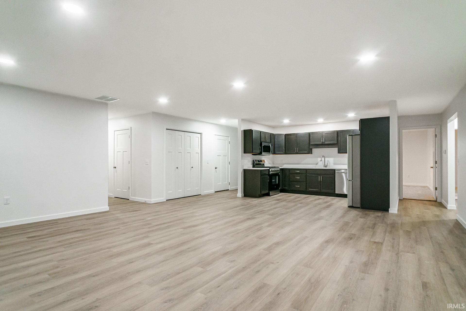 Kitchen with open floor plan, light countertops, stainless steel appliances, light wood-style floors, and recessed lighting
