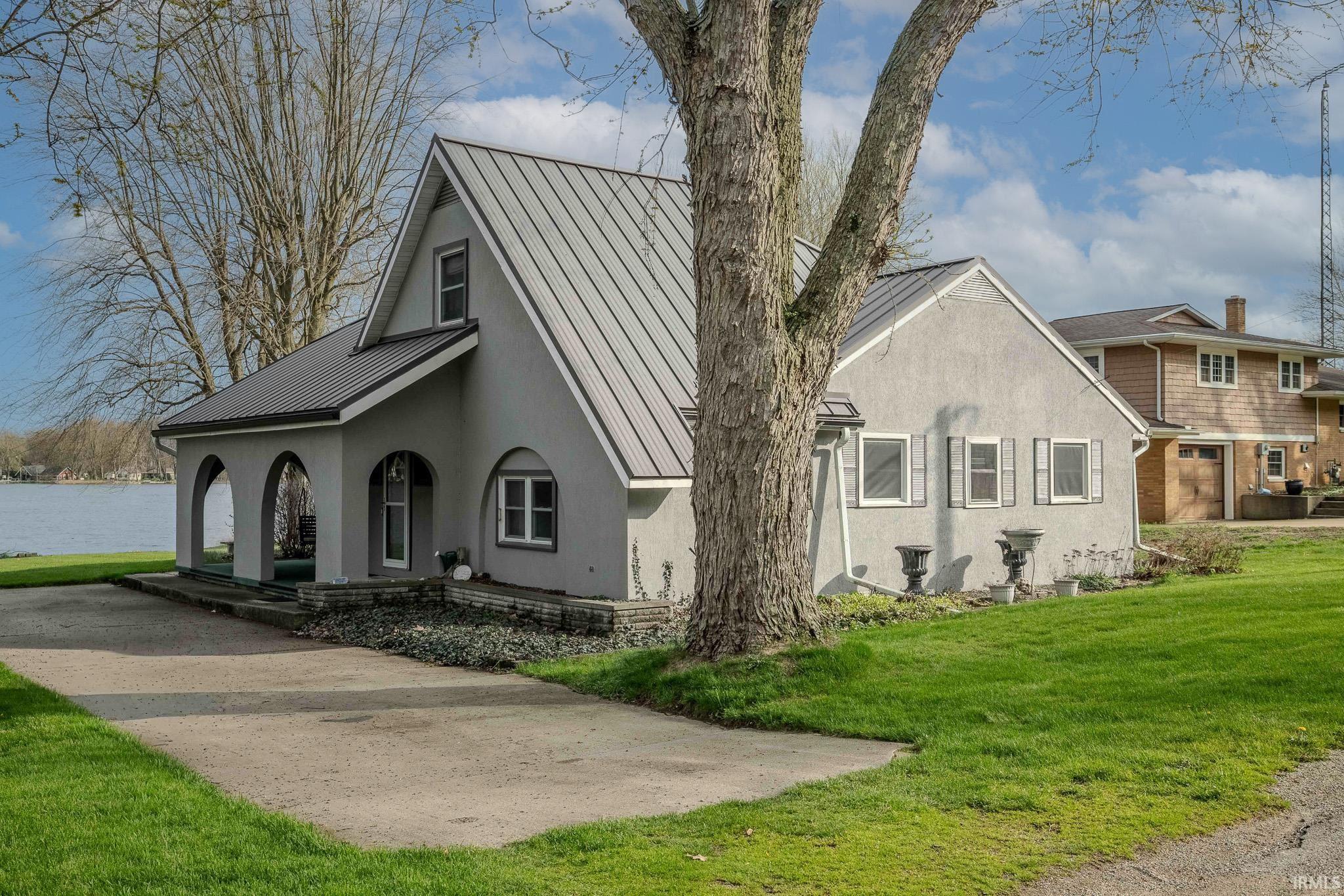 View of home's exterior featuring covered porch, a standing seam roof, stucco siding, and a lawn
