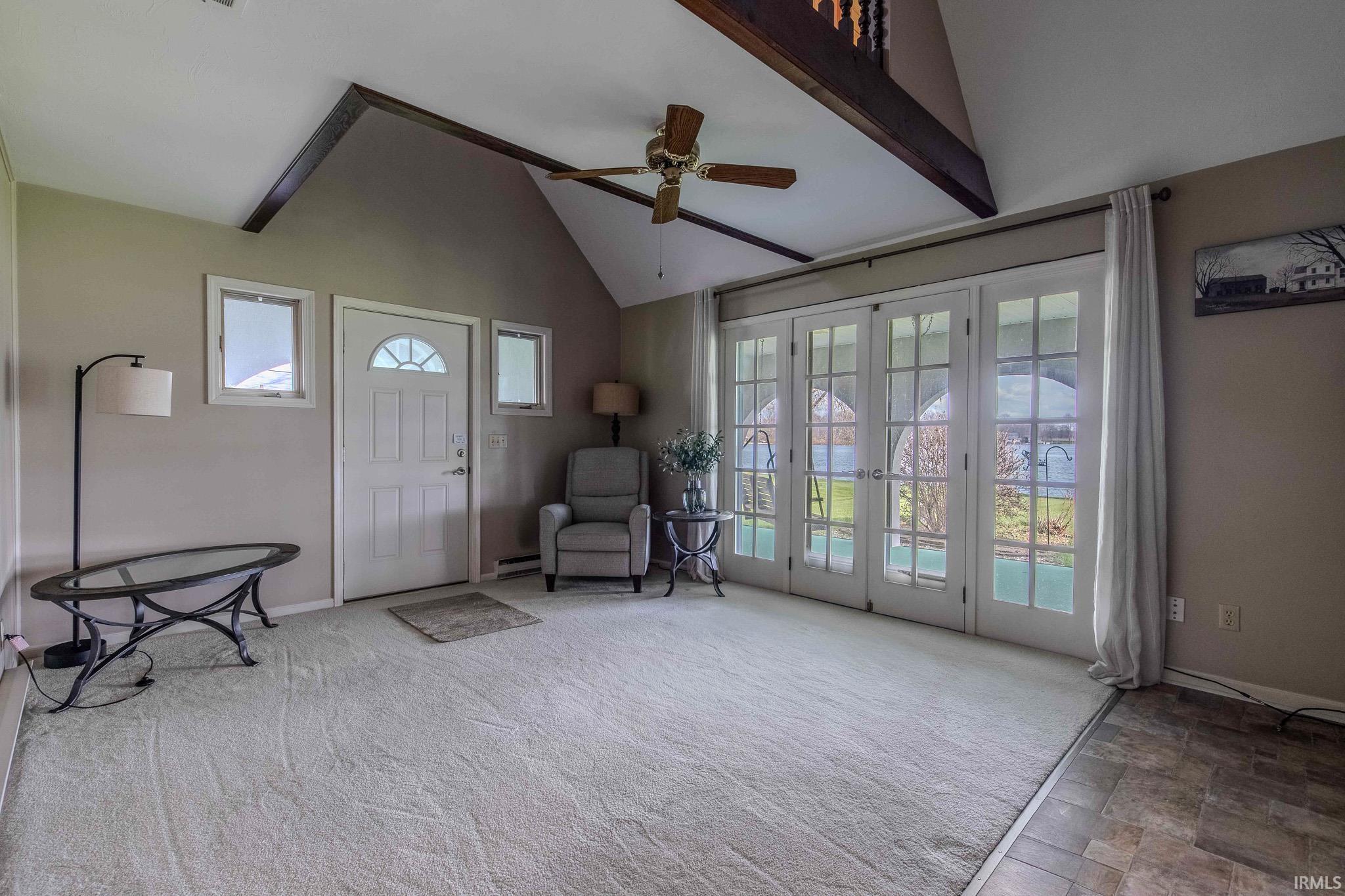 Entrance foyer featuring ceiling fan, lofted ceiling, light carpet, french doors, and baseboard heating