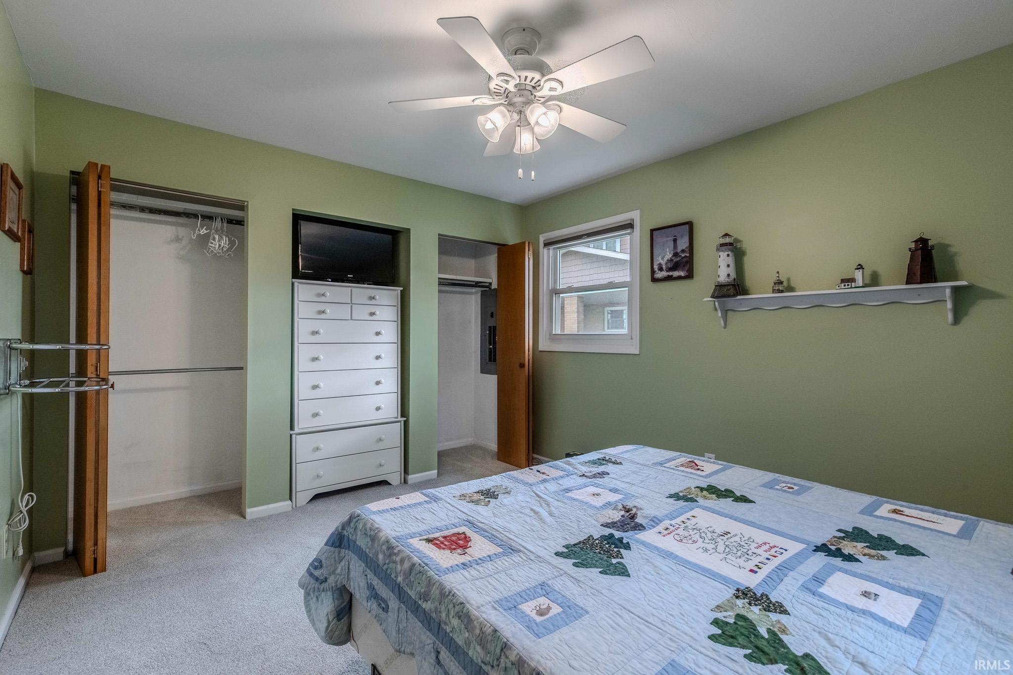 Bedroom with multiple closets, light carpet, and a ceiling fan