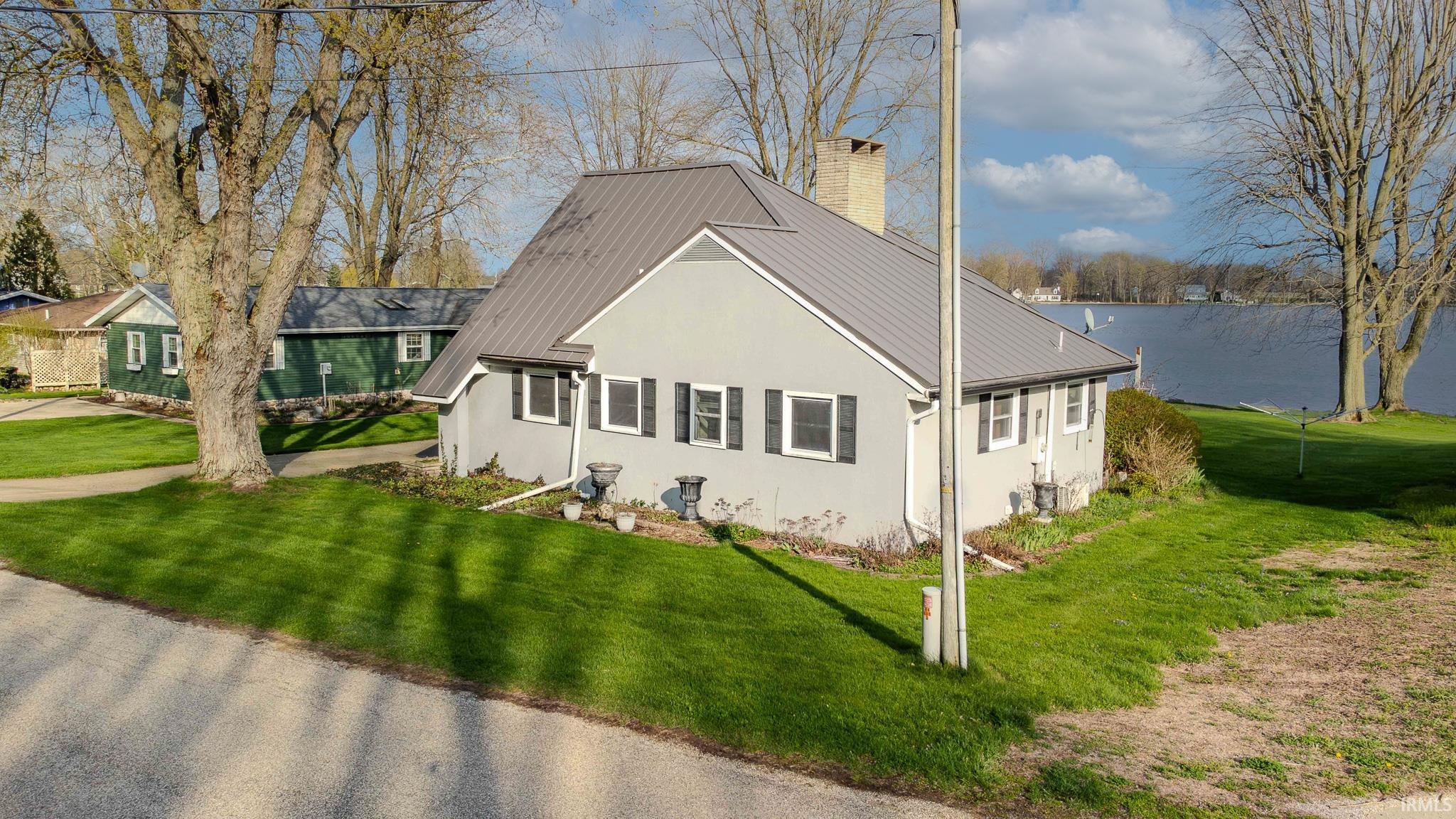 View of front of home featuring a chimney, a front yard, and a metal roof