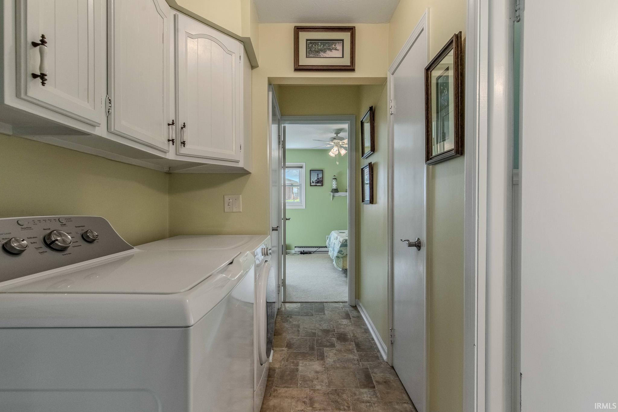Laundry room with stone finish flooring, cabinet space, independent washer and dryer, and a ceiling fan