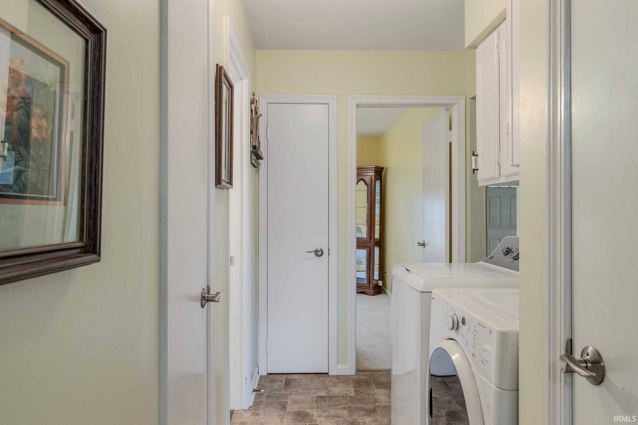 Laundry area featuring cabinet space, stone finish flooring, and independent washer and dryer