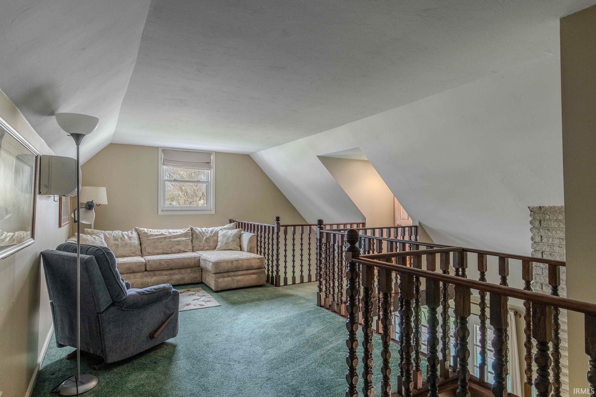 Living area featuring carpet floors and vaulted ceiling