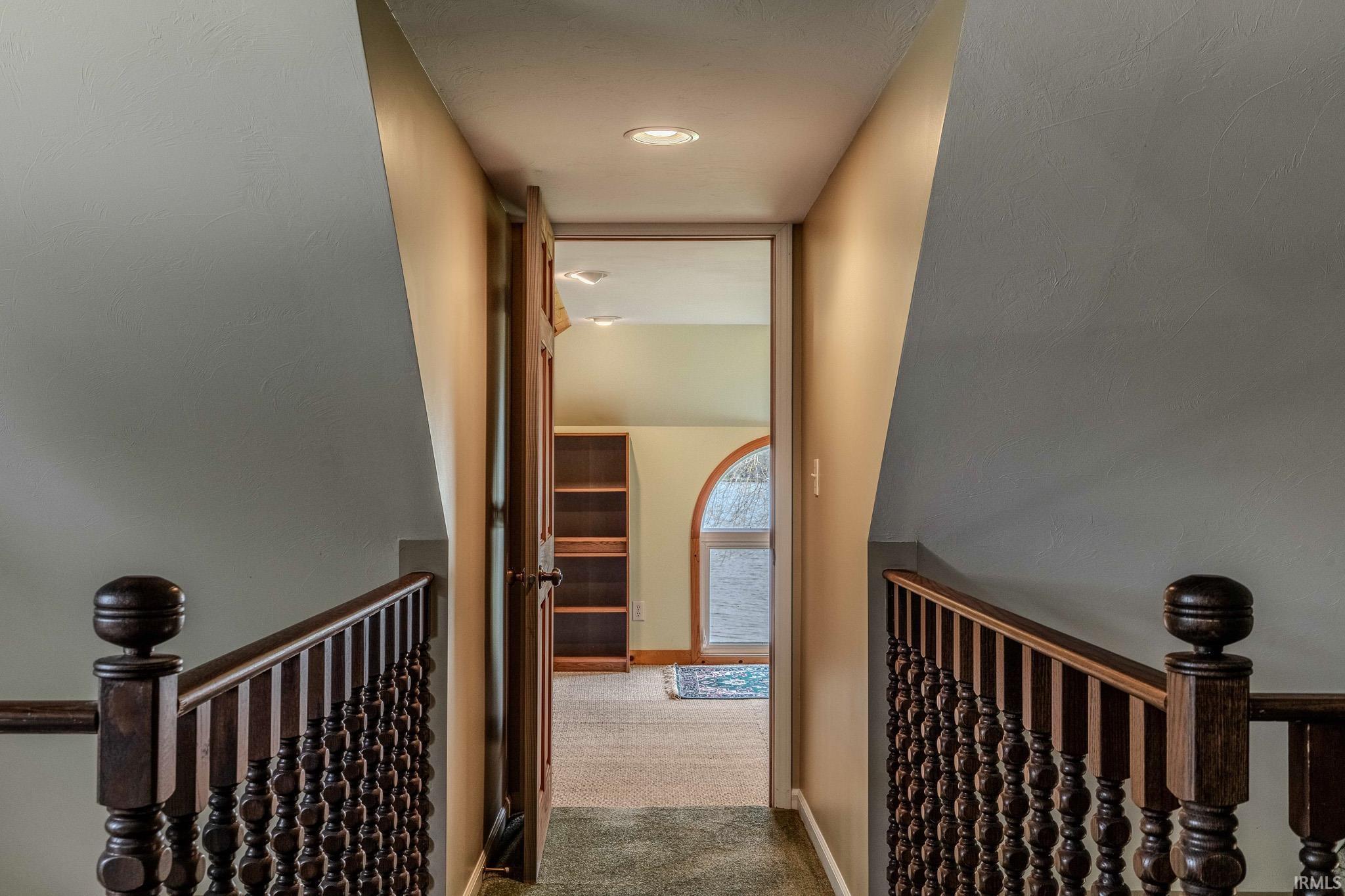 Corridor with an upstairs landing and light colored carpet
