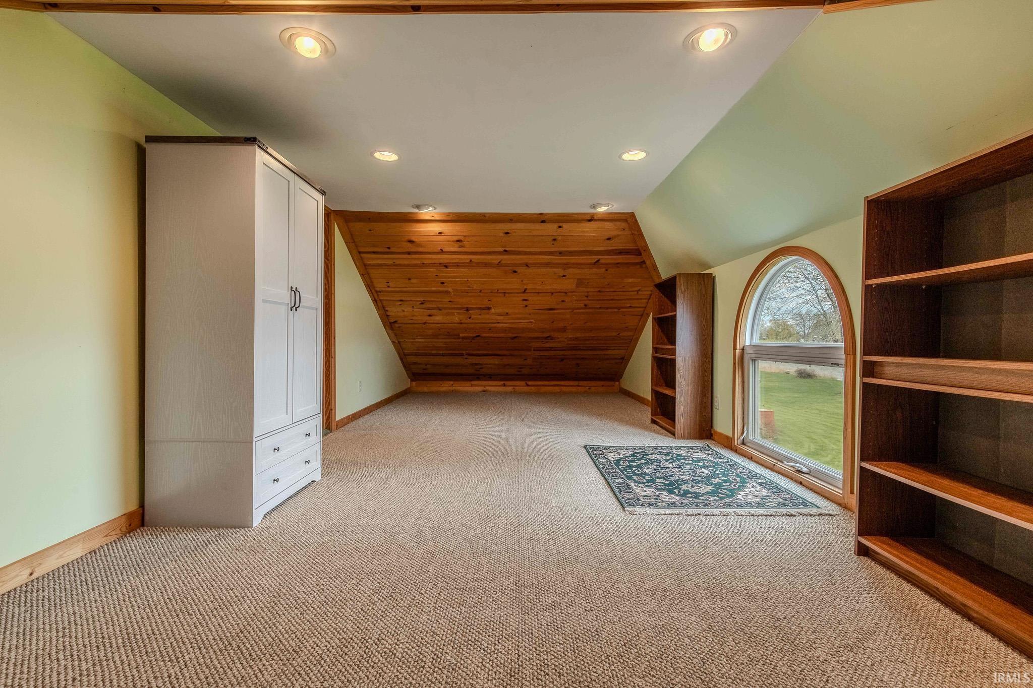 Additional living space with lofted ceiling, recessed lighting, and light carpet