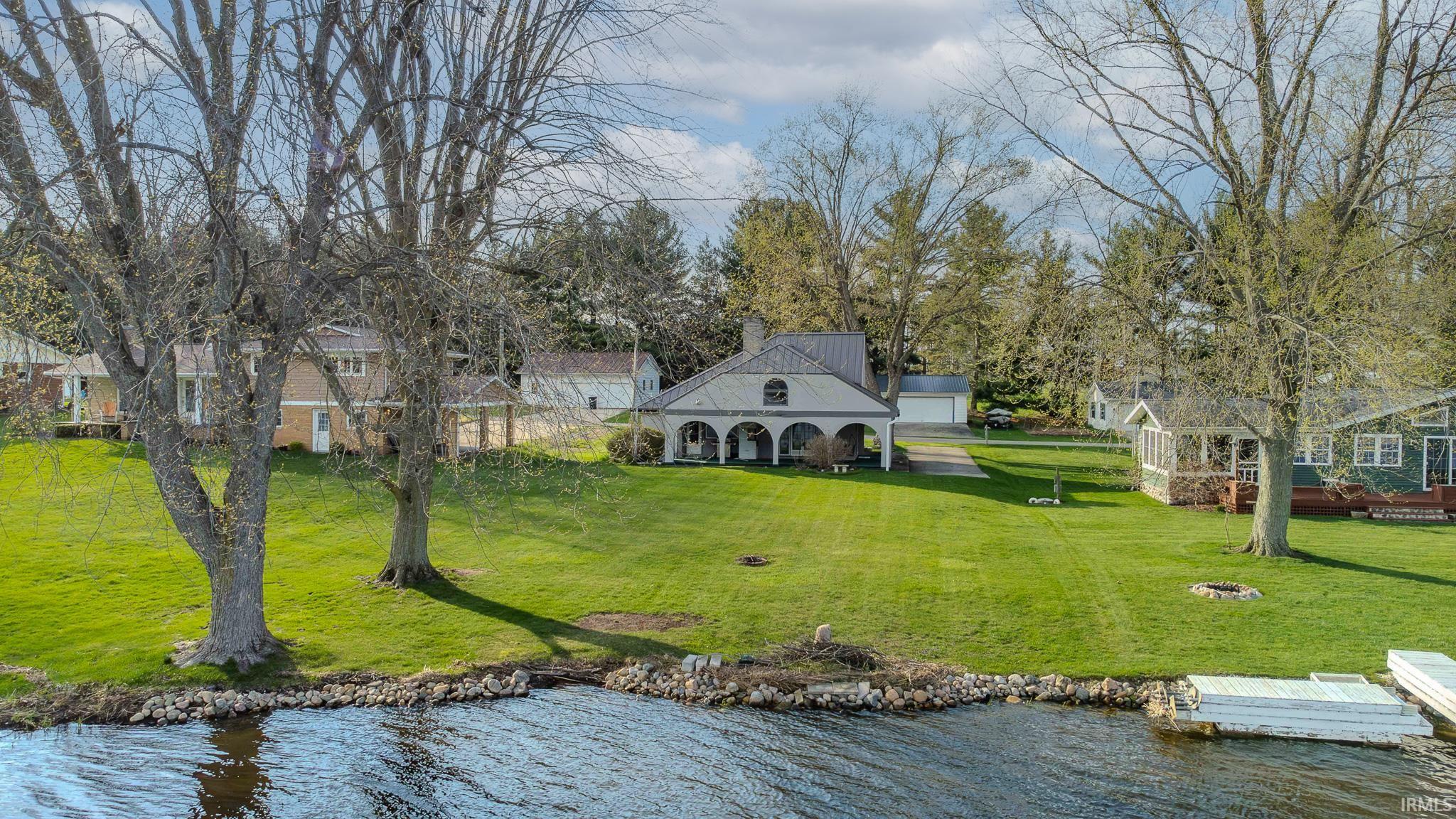 Back of house with a water view, a lawn, a chimney, and view of wooded area