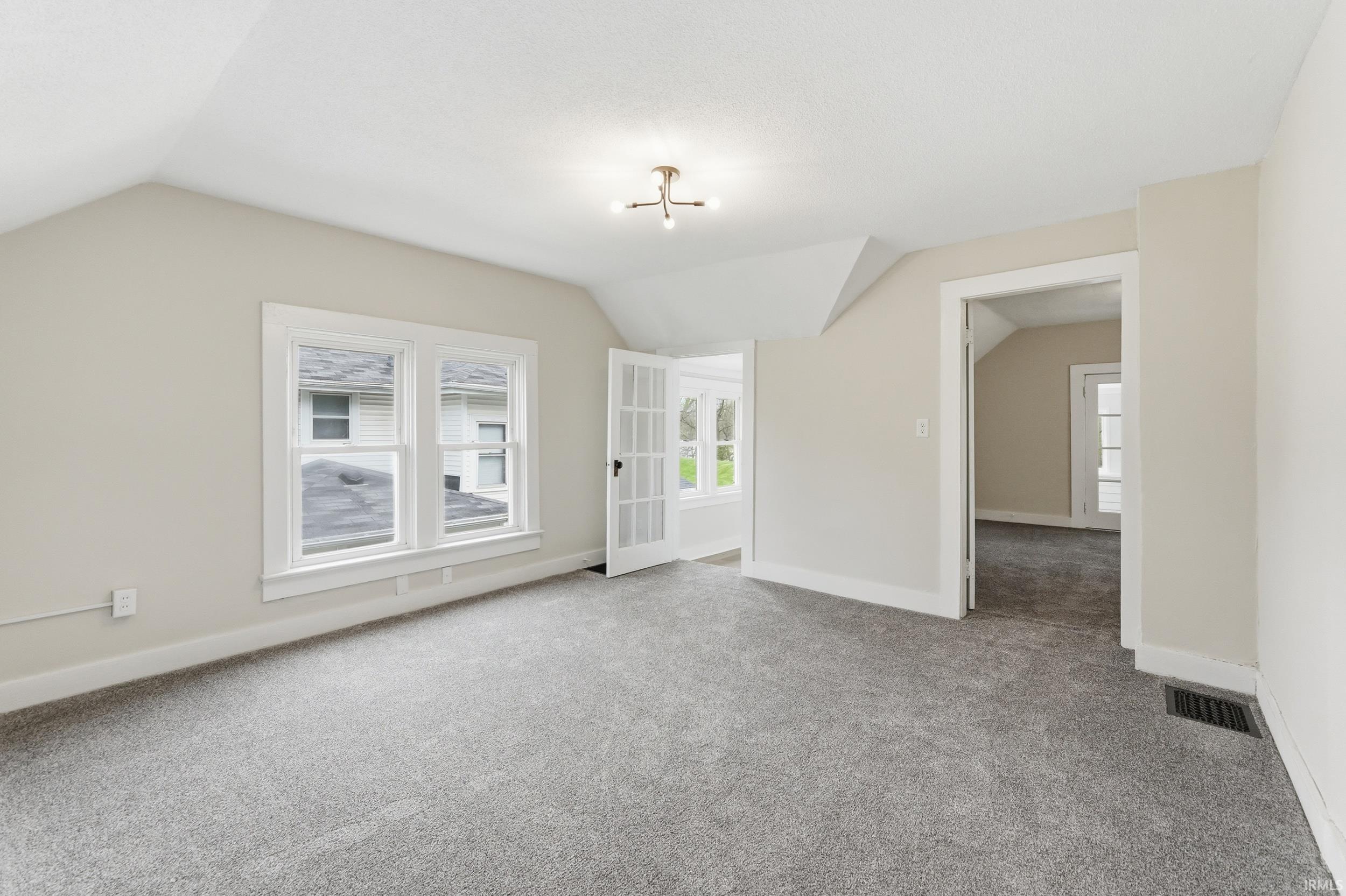 Unfurnished room featuring light colored carpet and healthy amount of natural light