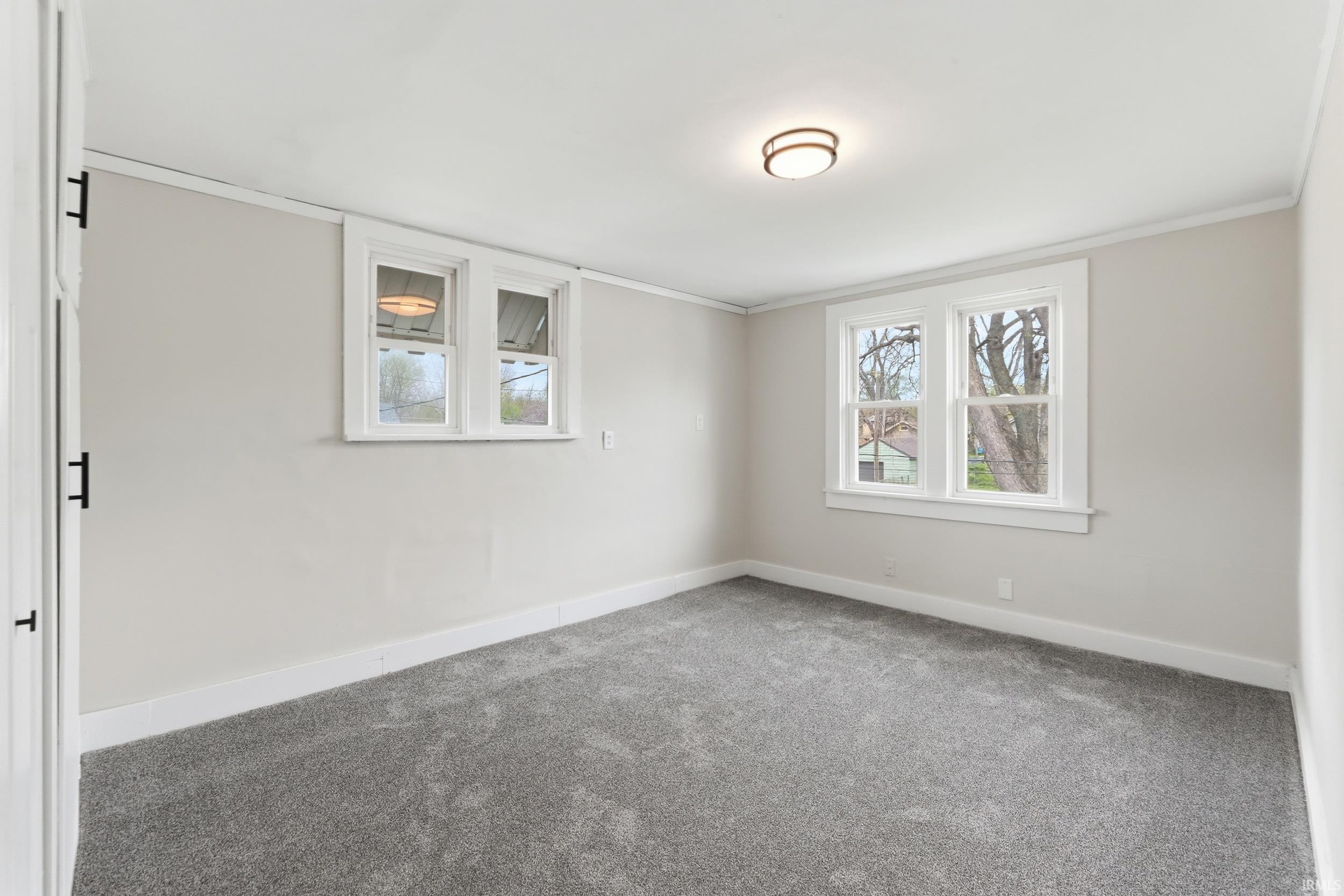 Carpeted empty room with baseboards and crown molding
