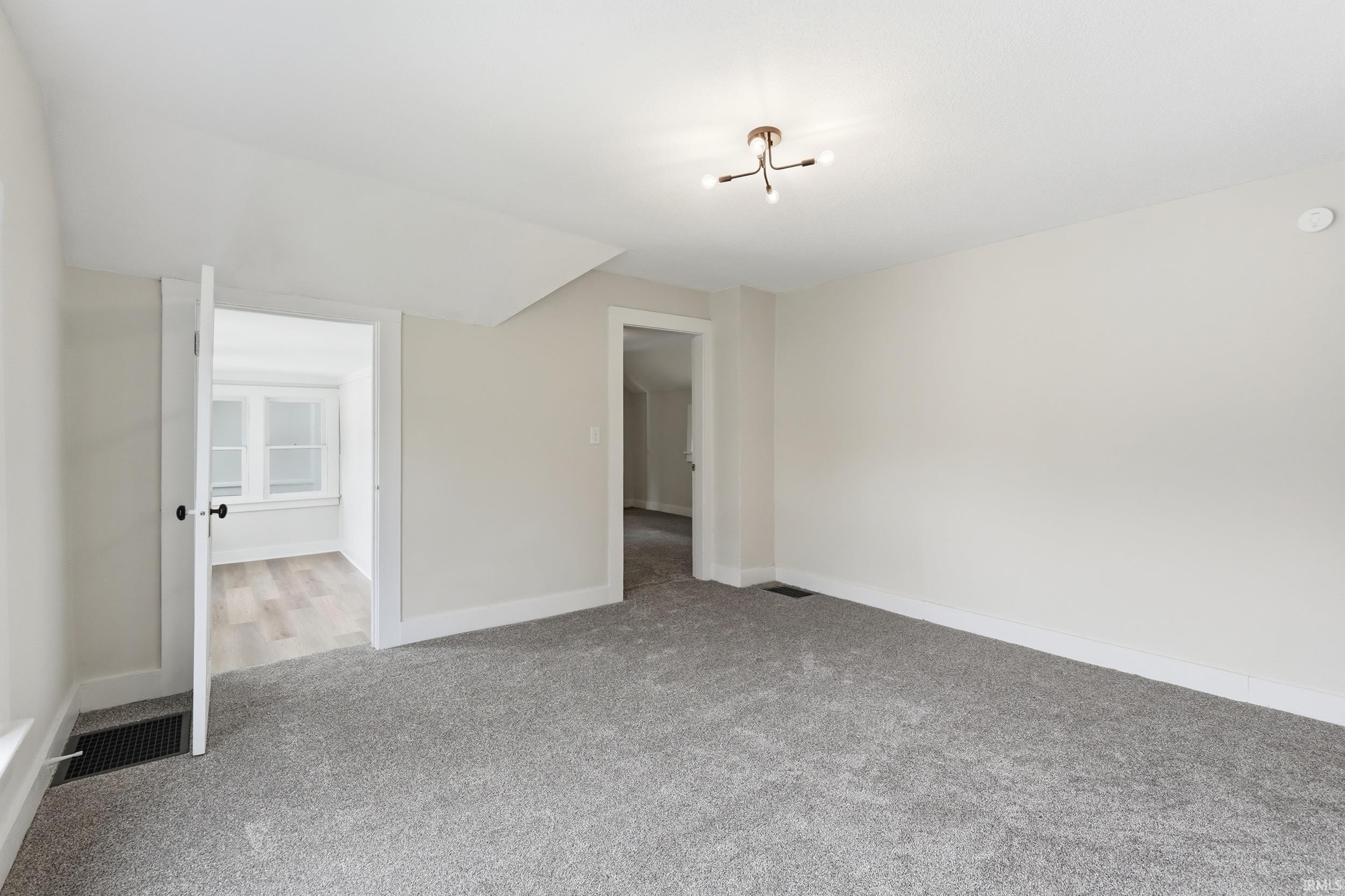 Unfurnished bedroom featuring light carpet and vaulted ceiling