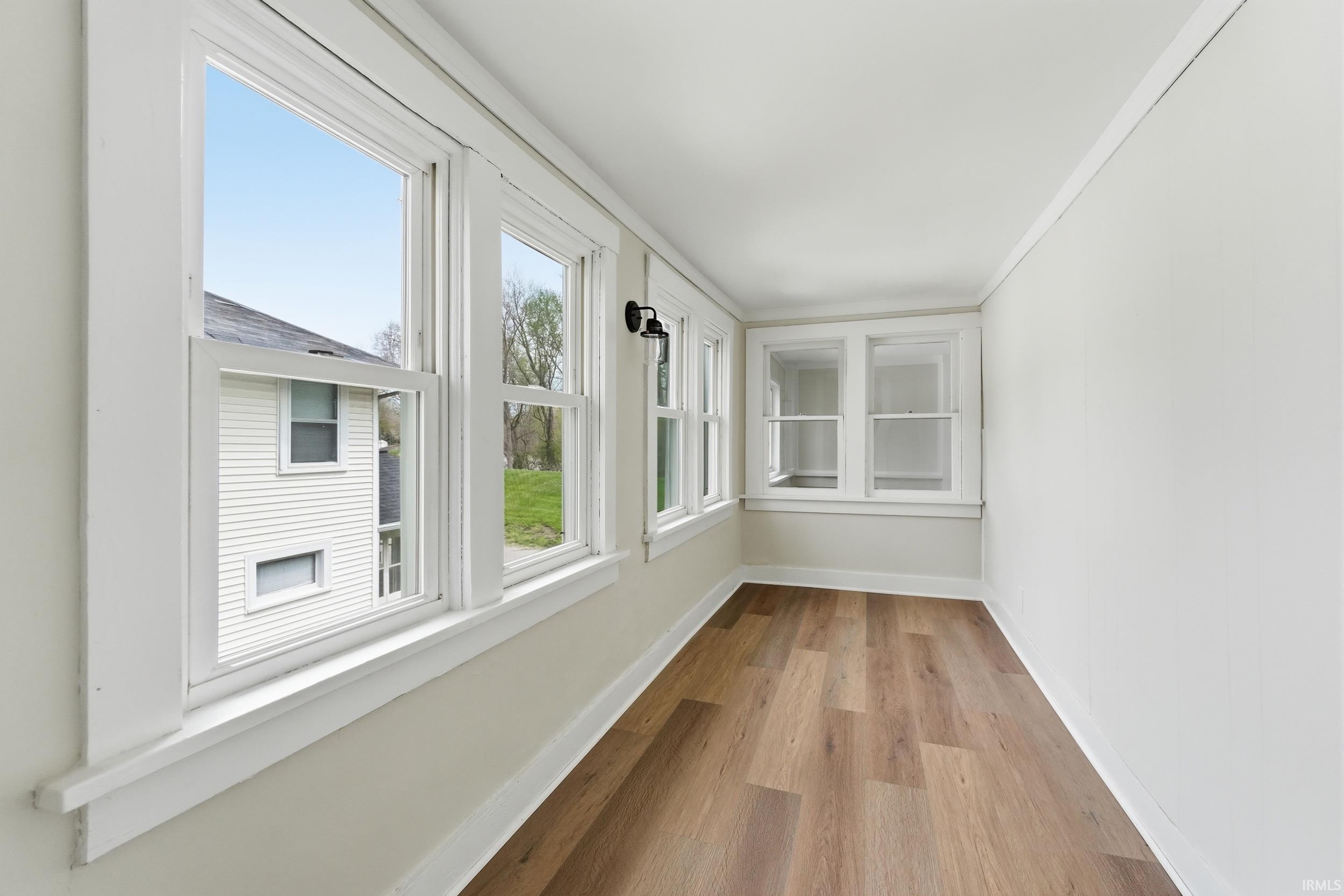 Unfurnished sunroom with wood finished floors and baseboards