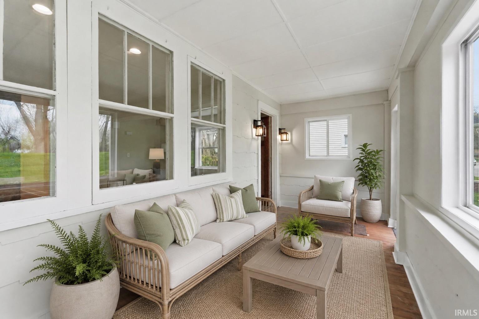Enclosed porch featuring multiple large windows, shiplap wall accents, and an exposed wood ceiling